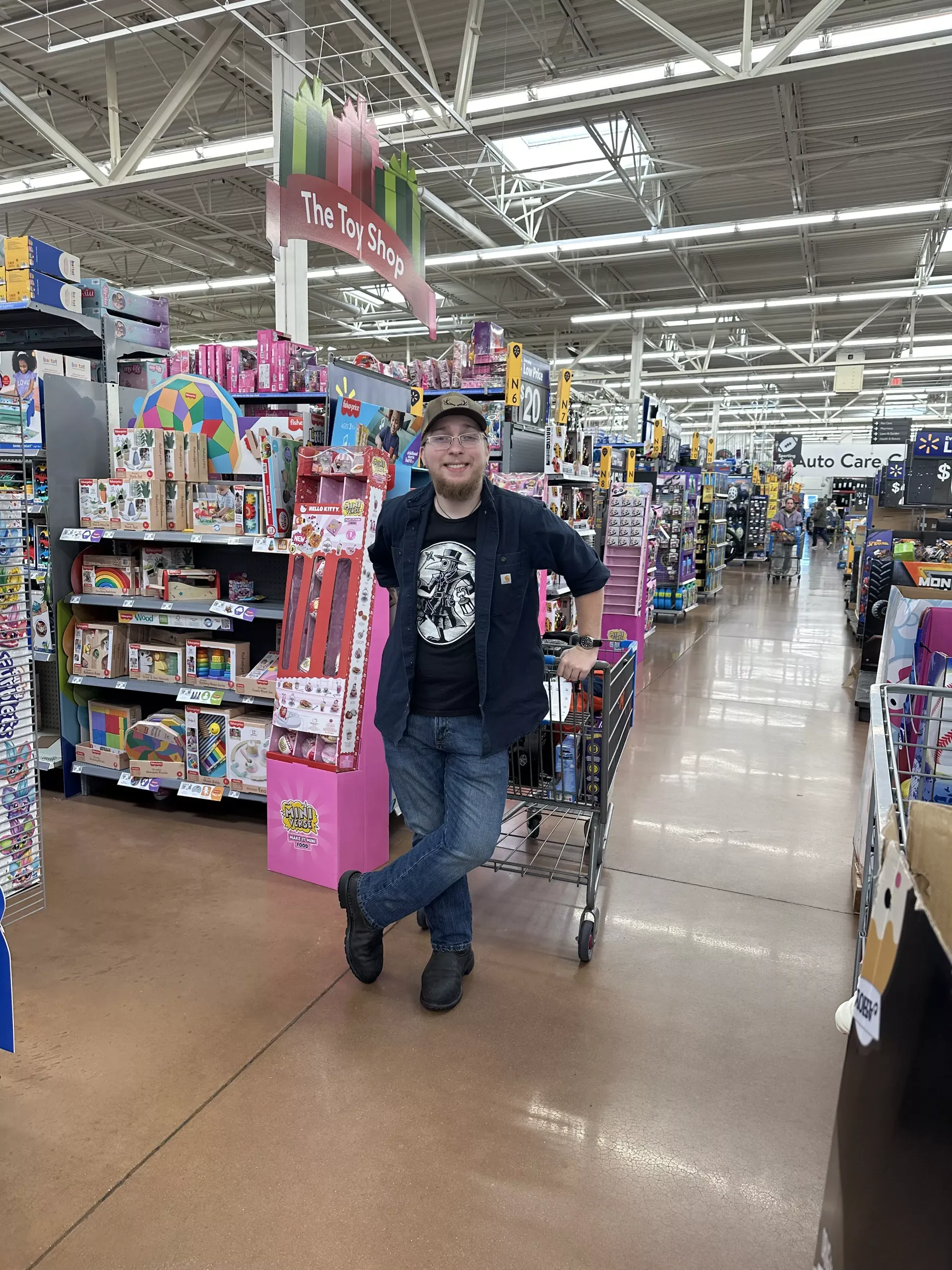 Person leaning on a shopping cart in a brightly lit store aisle with colorful merchandise.