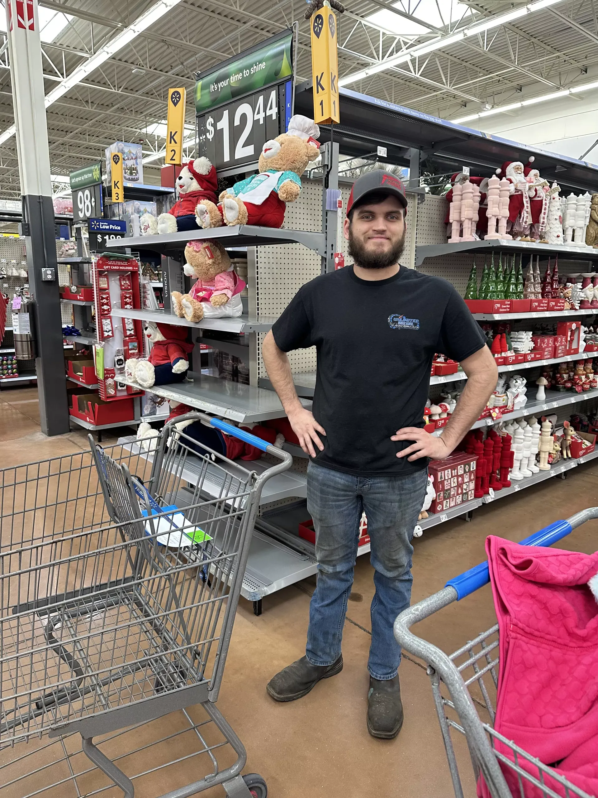 Man standing in a grocery aisle beside shopping carts and pet supplies, hands on hips.