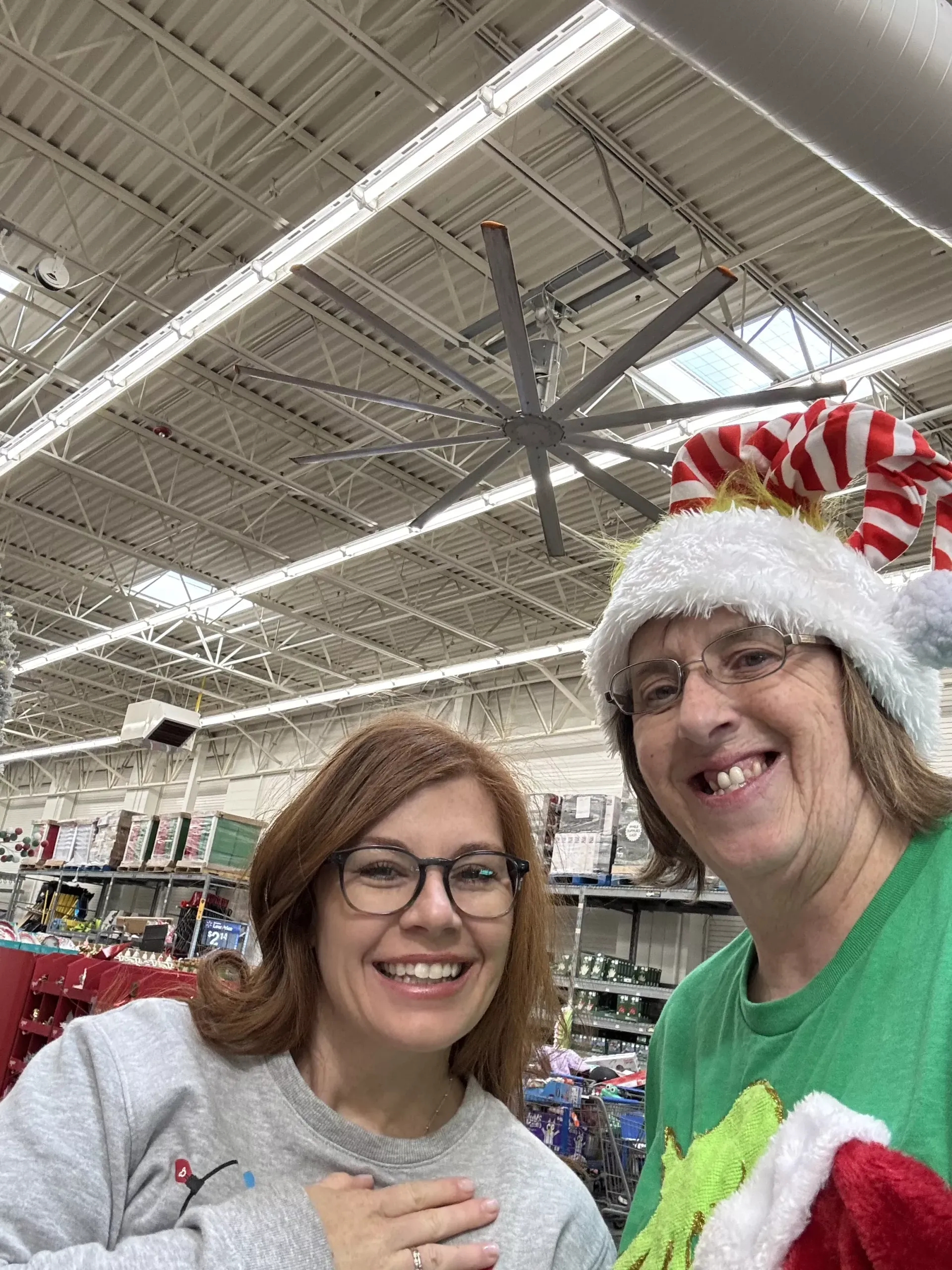 Two smiling people in festive hats posing under store ceiling lights