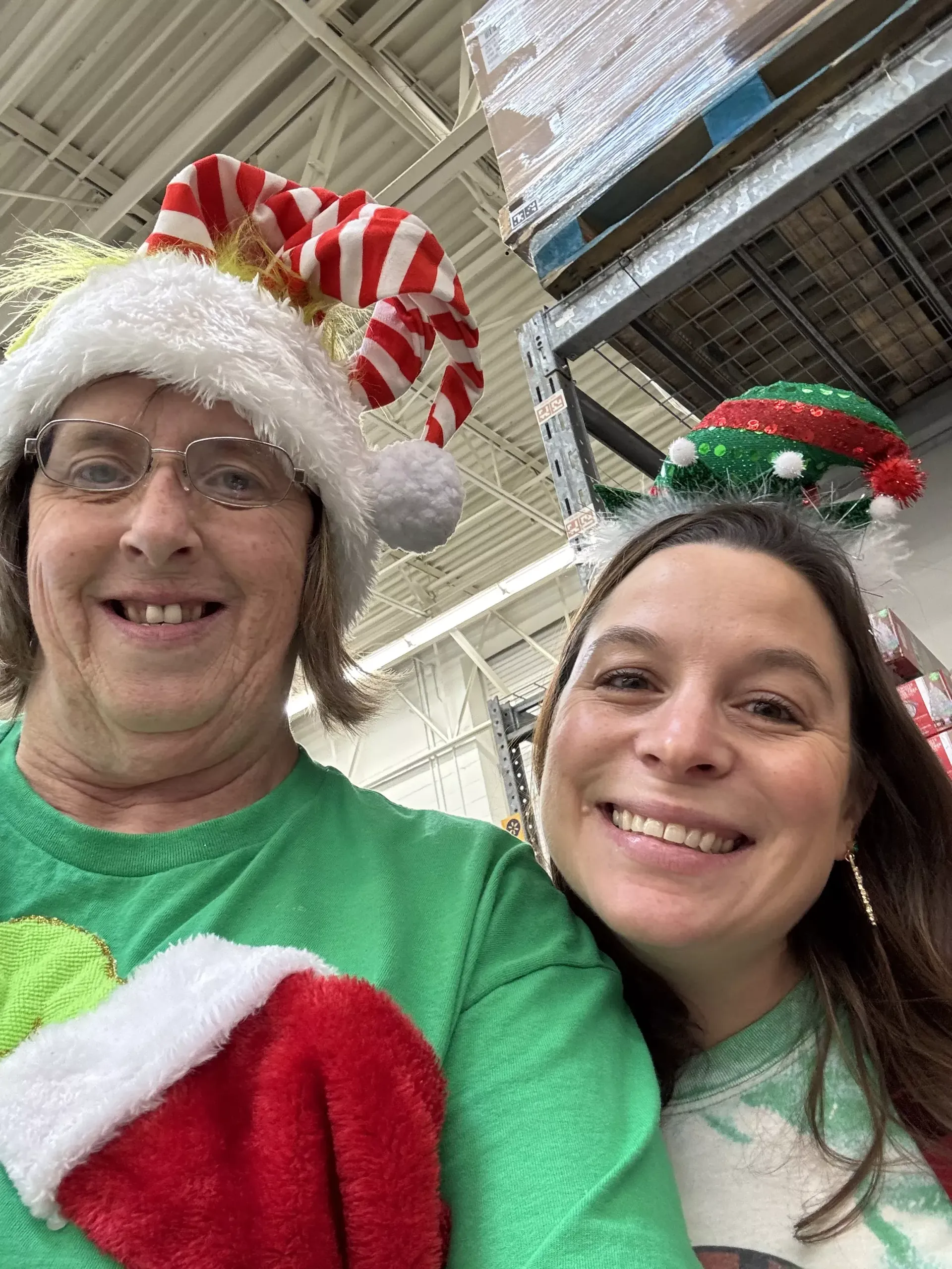 Two smiling people wearing festive holiday hats in a store aisle