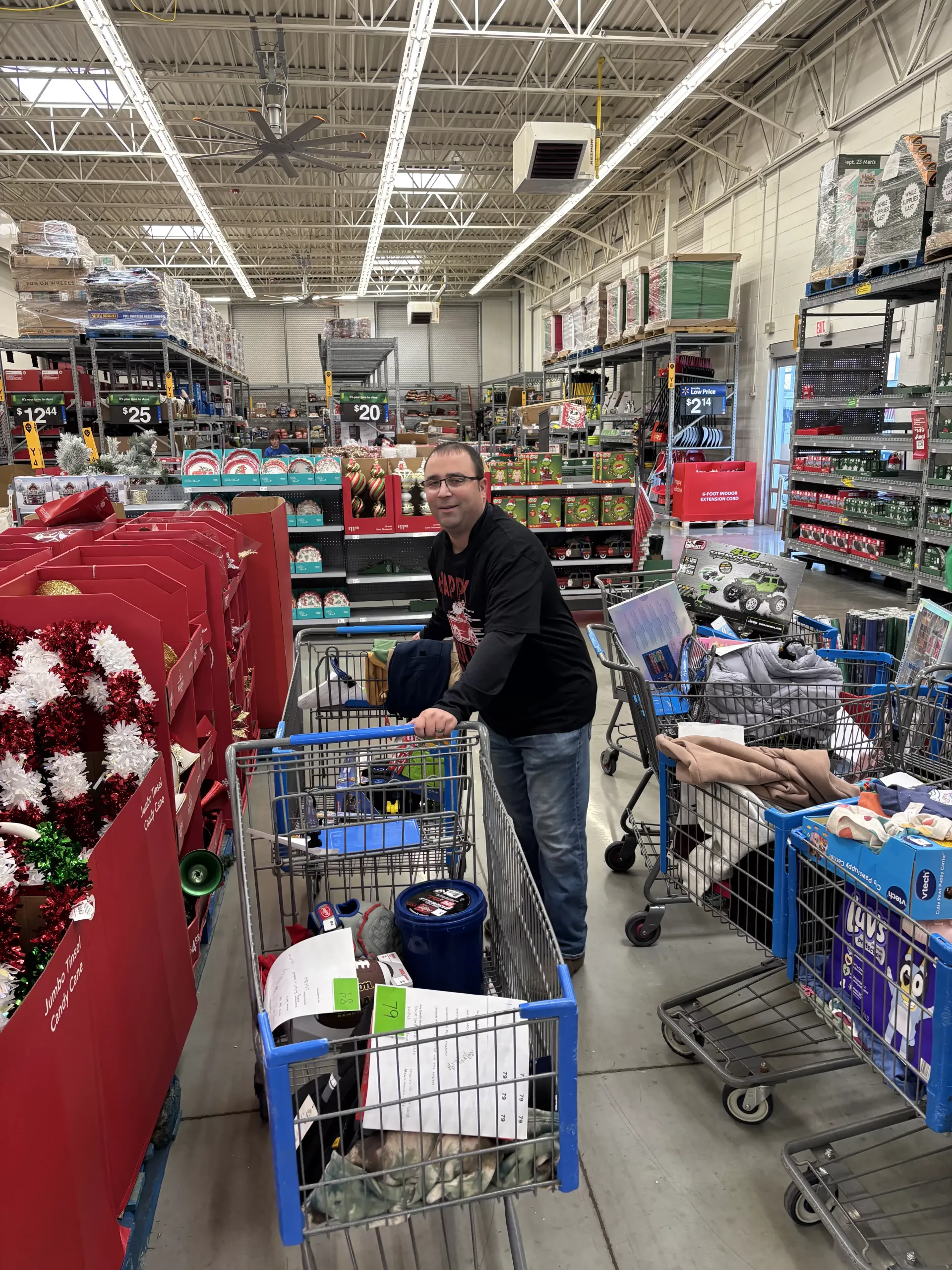 Shopper pushing a cart in a crowded warehouse store aisle with holiday decorations and stacked merchandise