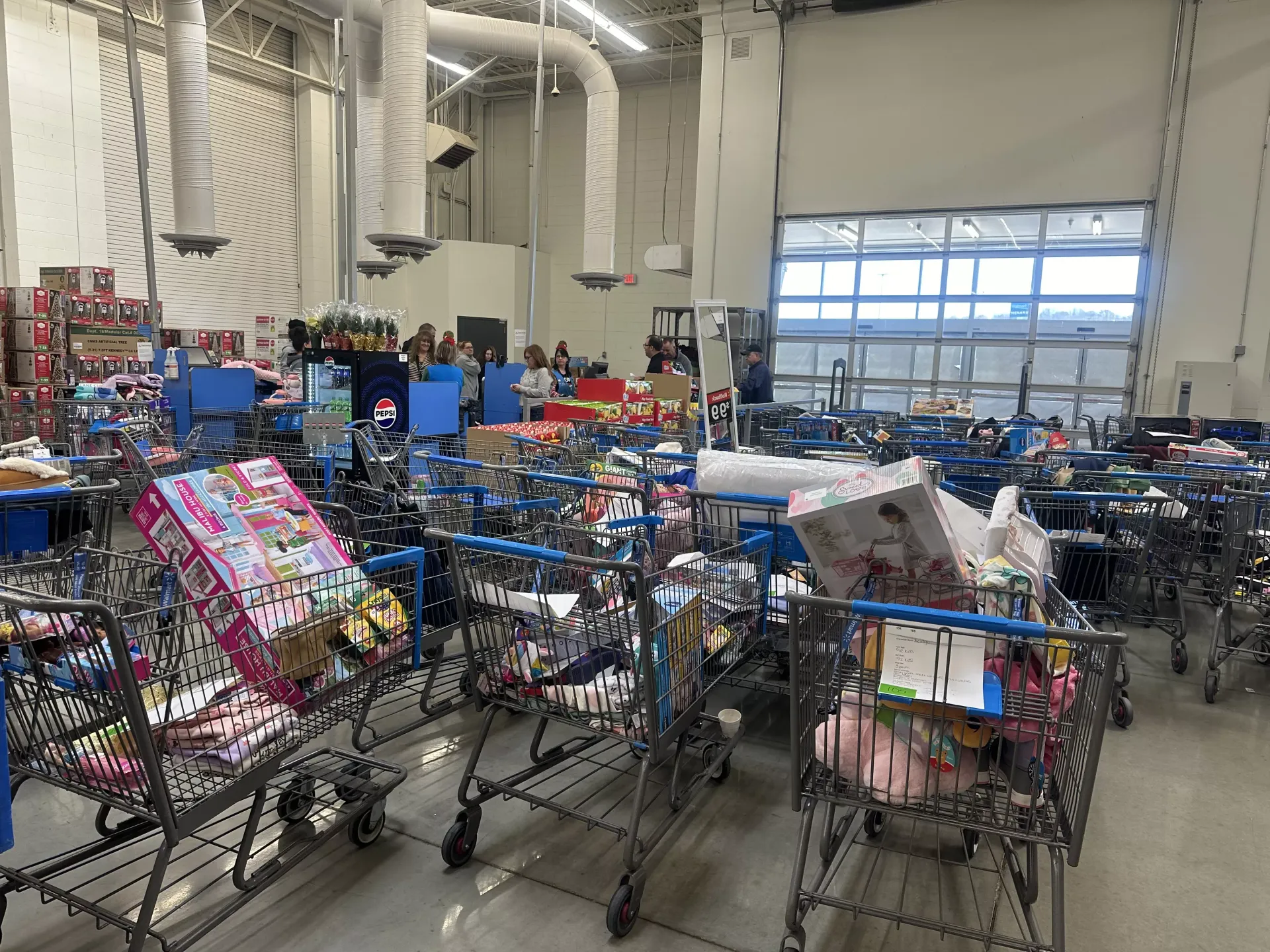 Warehouse with rows of shopping carts packed with assorted items under bright industrial lights
