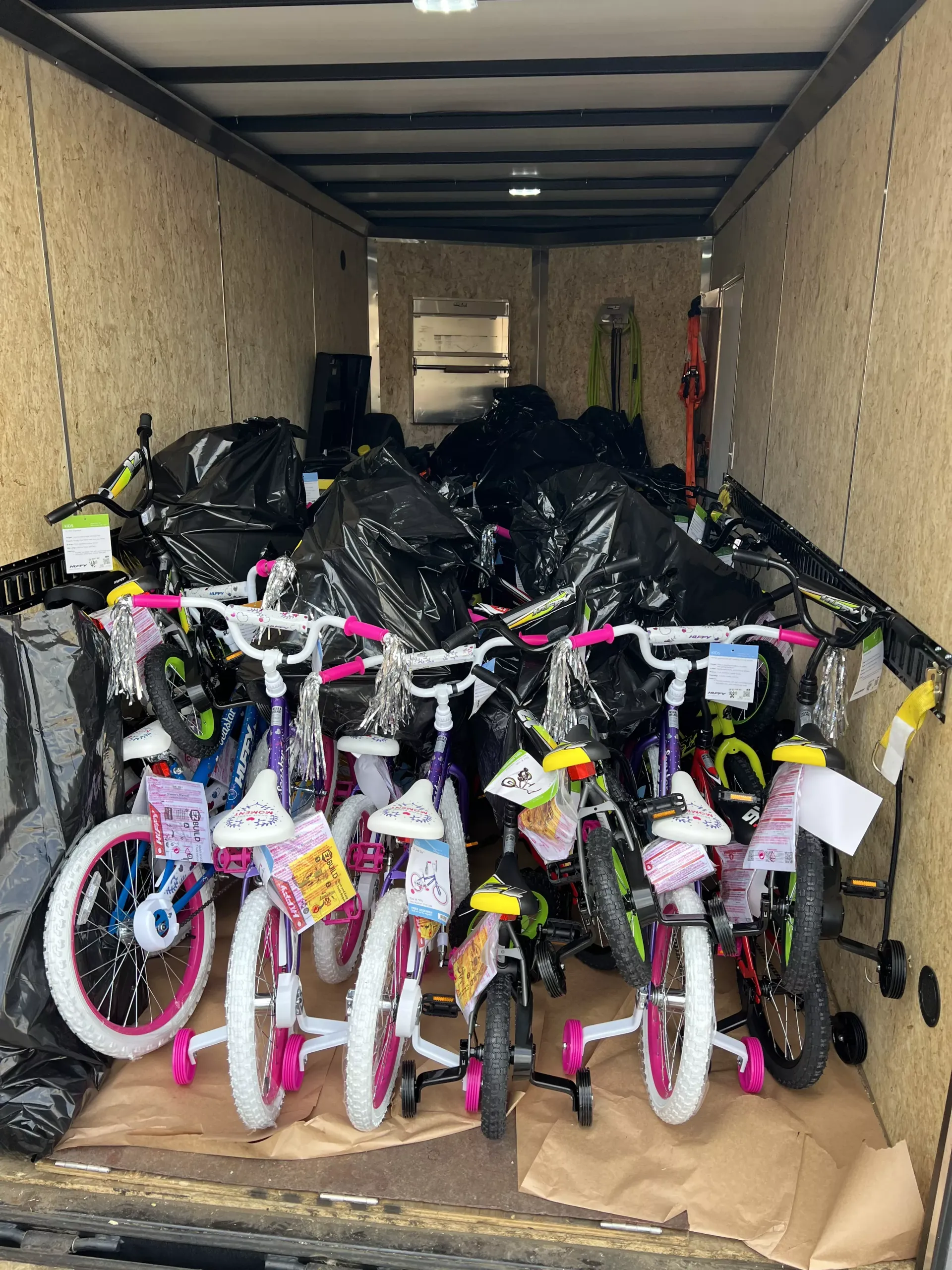 Trailer loaded with many children’s bicycles wrapped in black plastic bags
