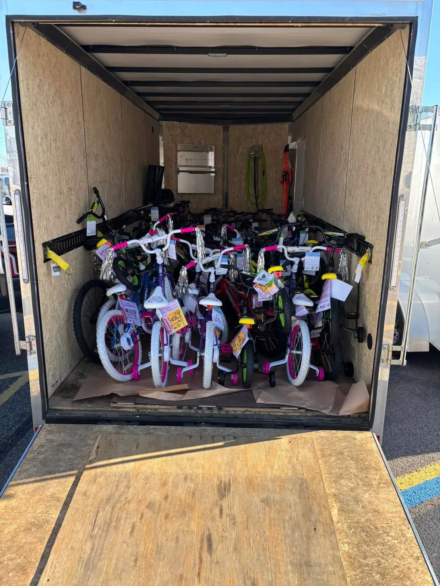 Open trailer filled with stacked children’s bicycles, including pink and white bikes.