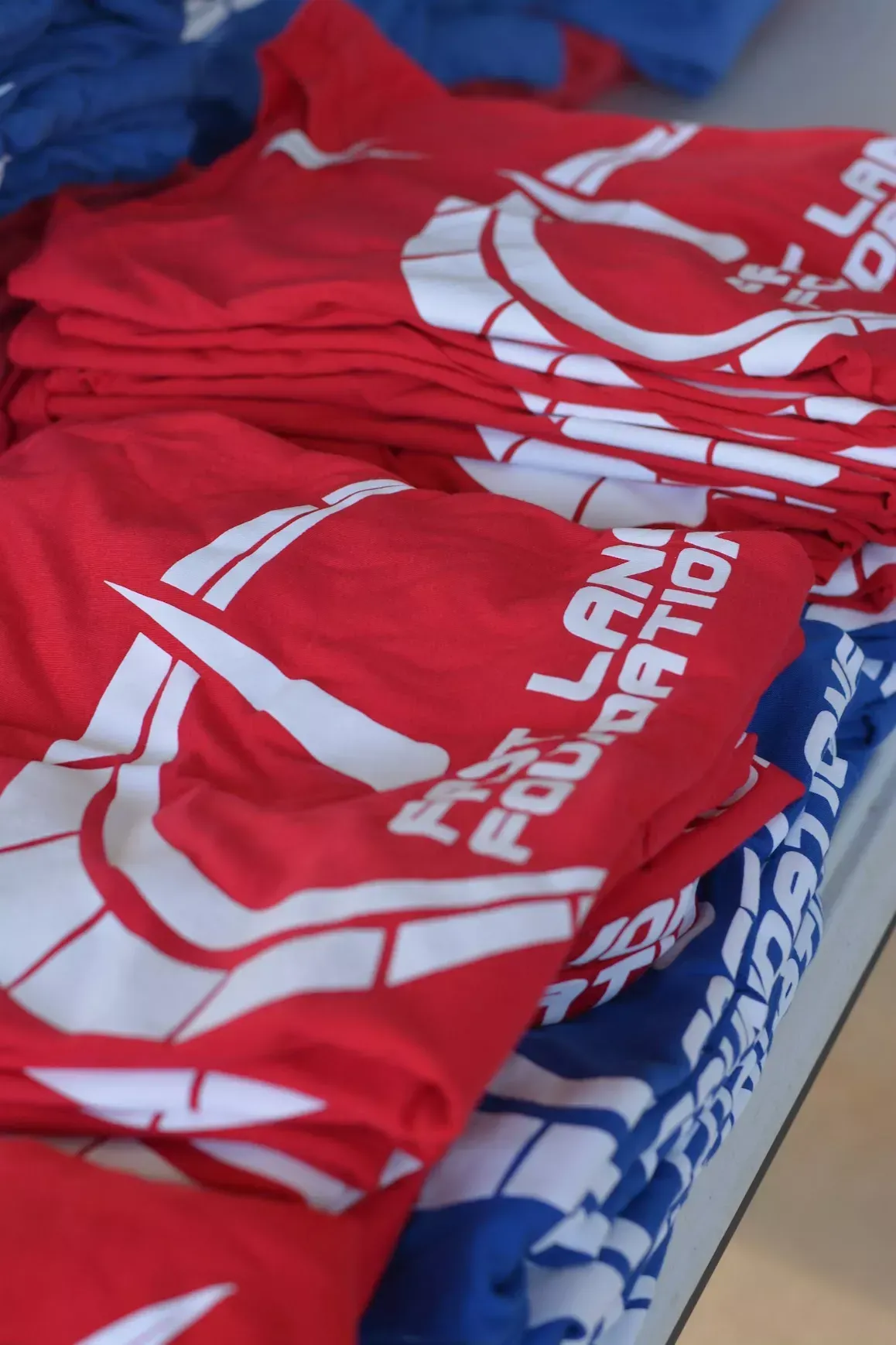 Red and blue event T-shirts stacked together on a table