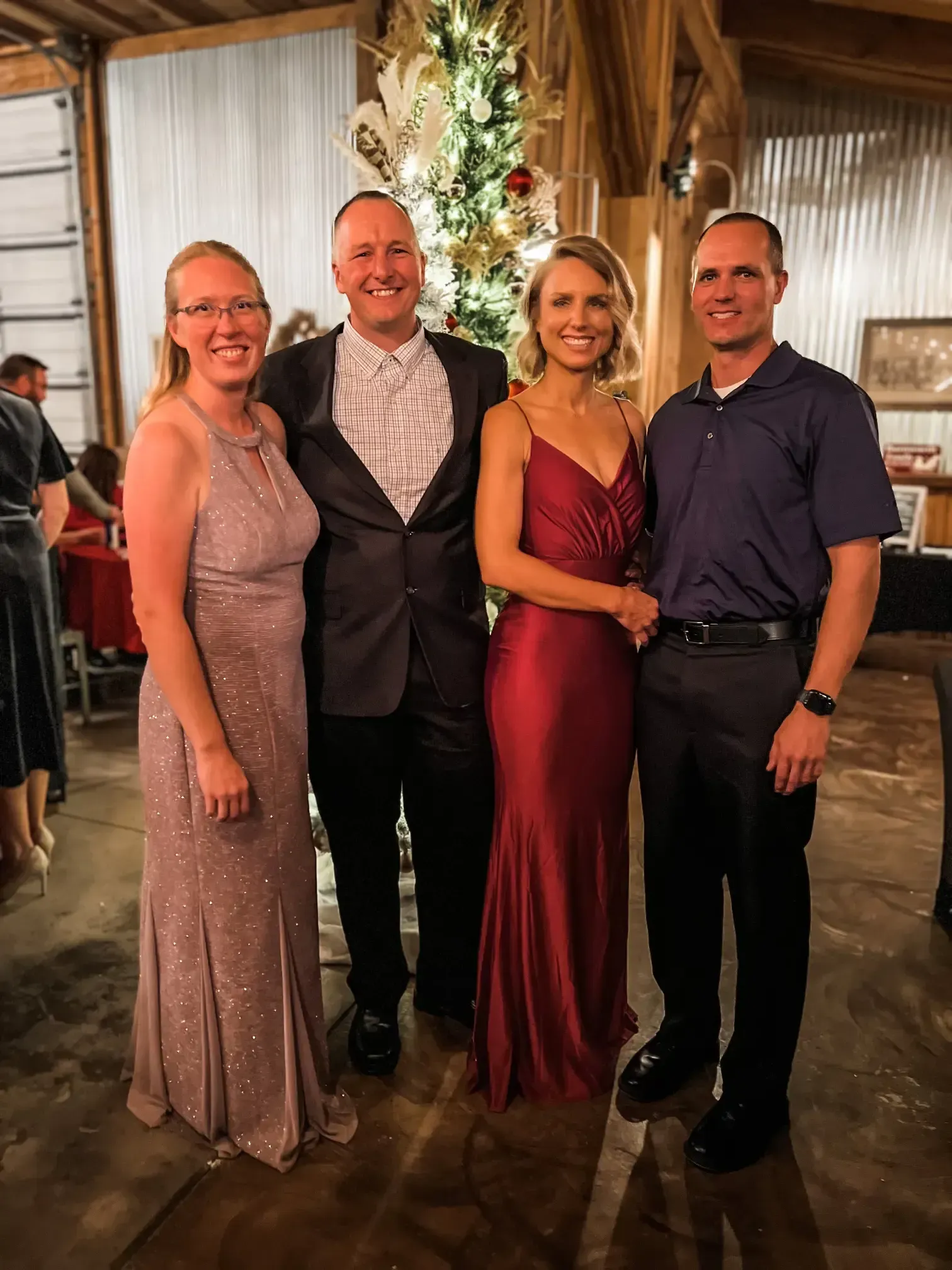 Four people posing together at an indoor event, dressed in formal evening attire.
