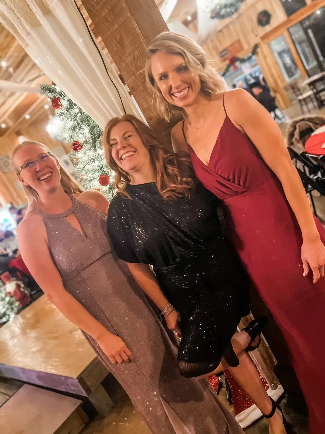 Three people smiling in dresses at a formal indoor event