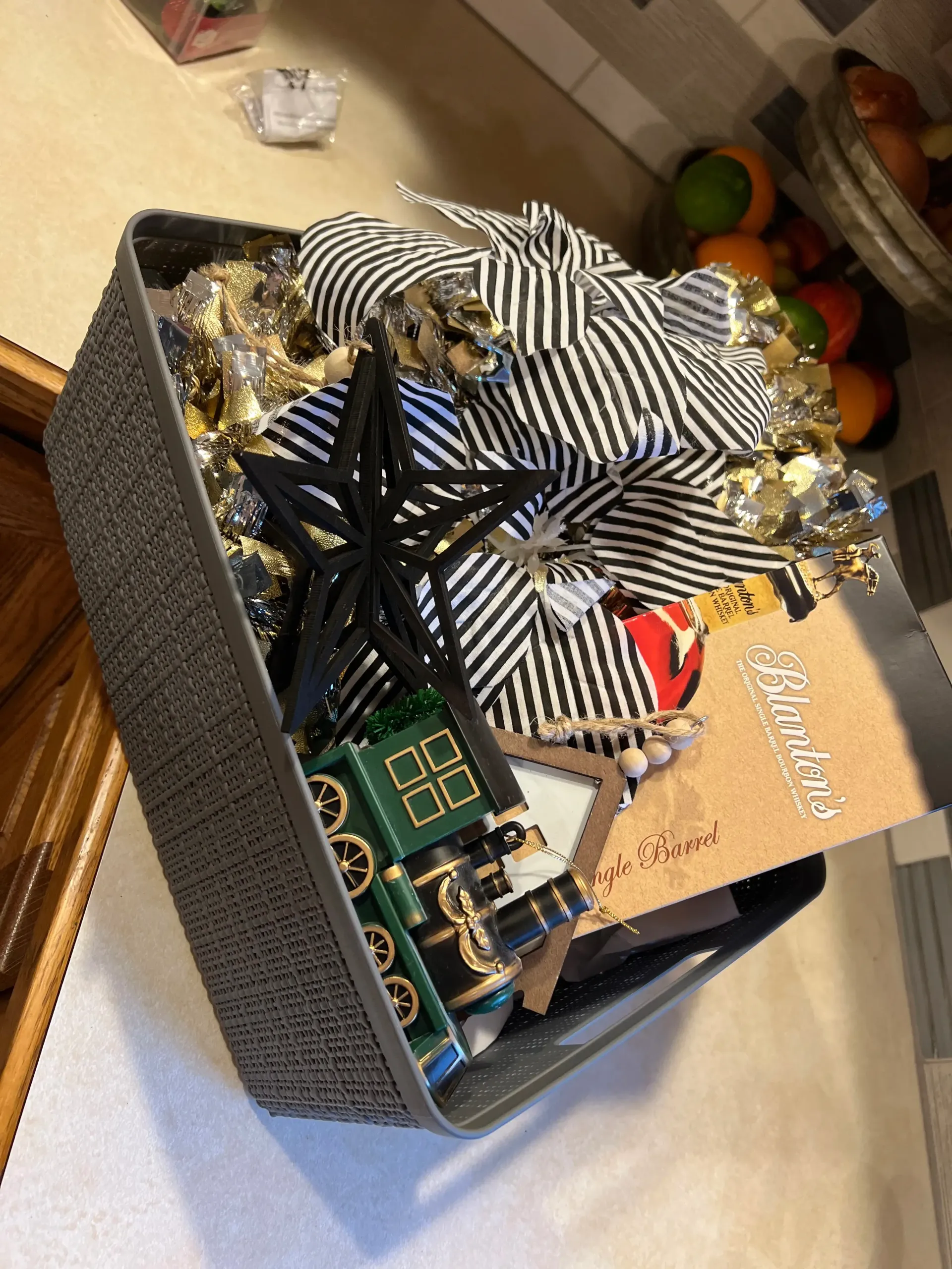 Decorative gift basket with black-and-white striped ribbon, gold accents, and a small greeting card on a table