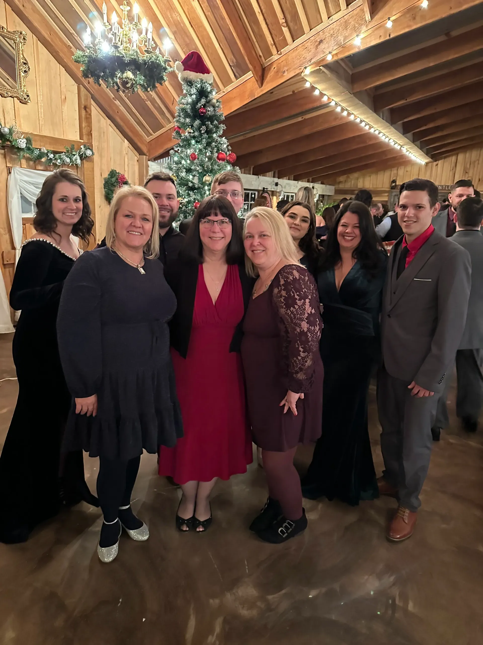 Group posing in a festive wooden lodge decorated with a Christmas tree and string lights.