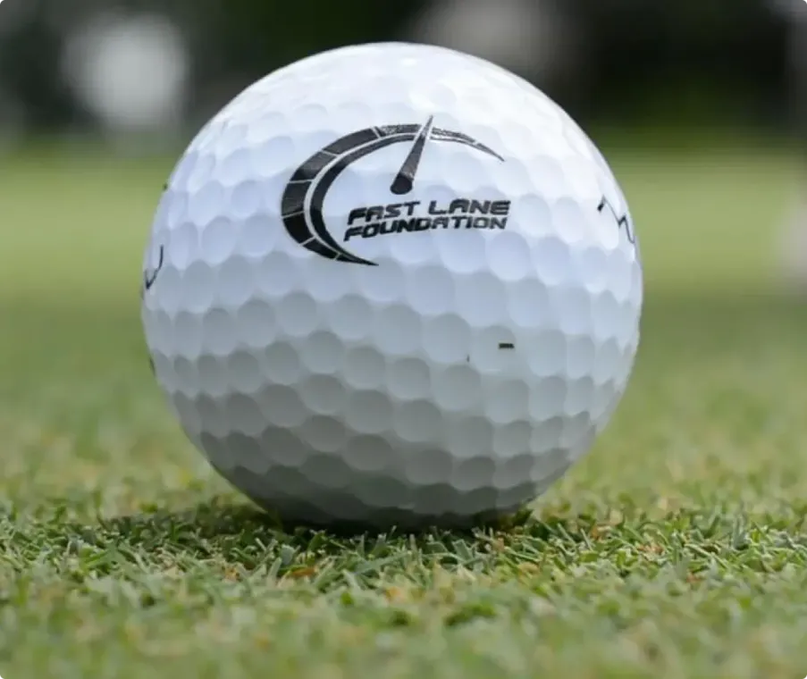 White golf ball on grass with First Land Foundation logo