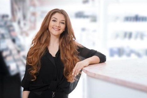 Eine Frau mit langen Haaren lehnt in einem Geschäft an einer Theke.