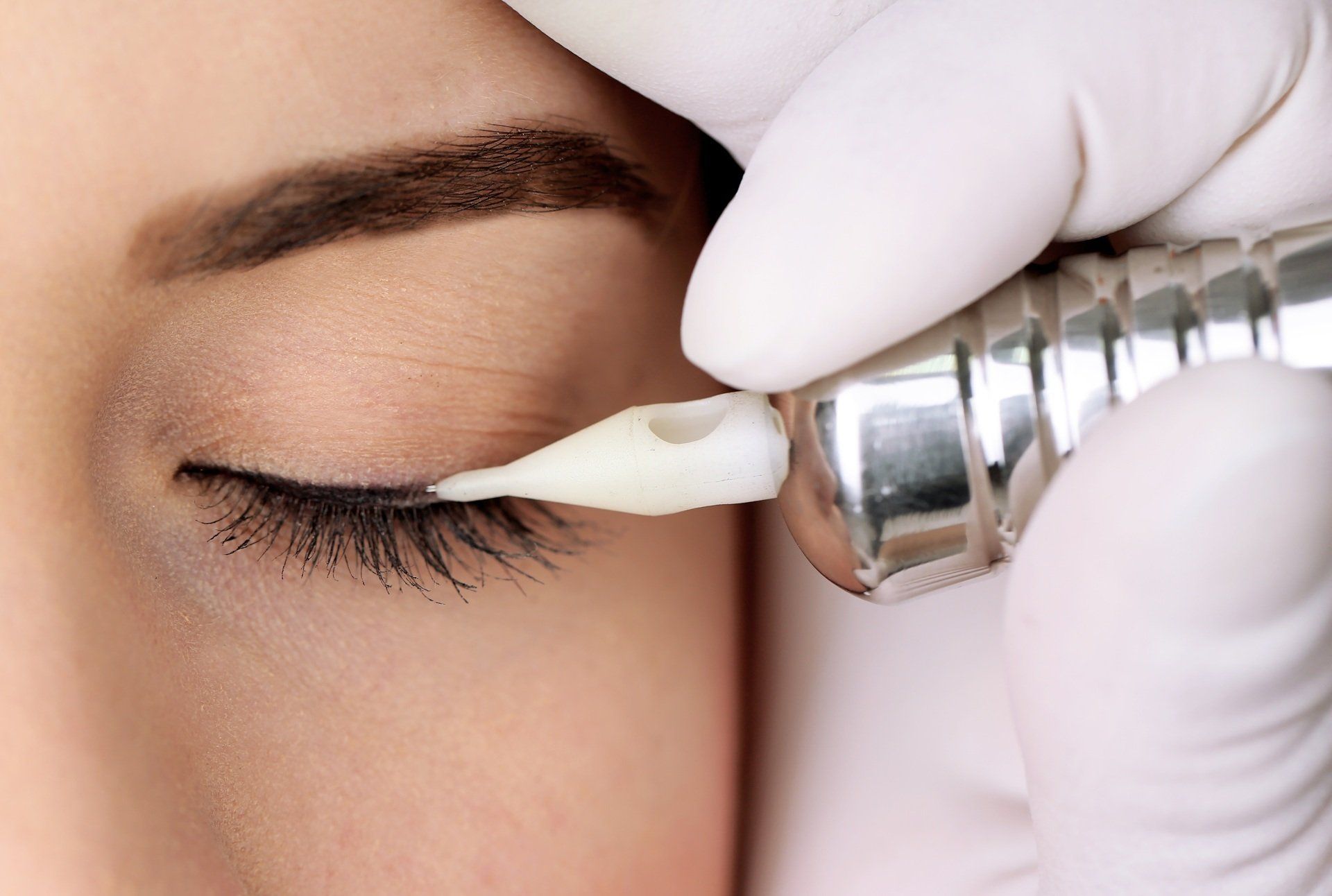 Eine Frau lässt sich ein permanentes Eyeliner-Tattoo aufs Auge stechen.