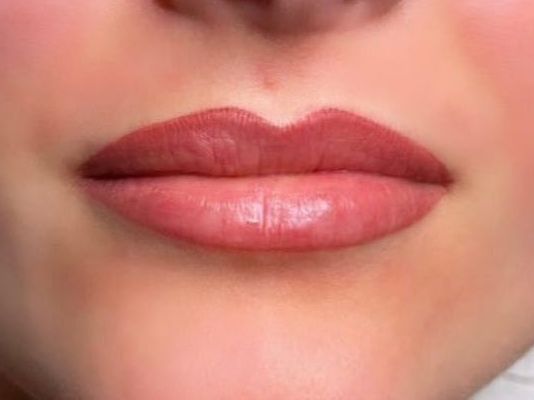 Eine Nahaufnahme der Lippen einer Frau mit rosa Lippenstift.