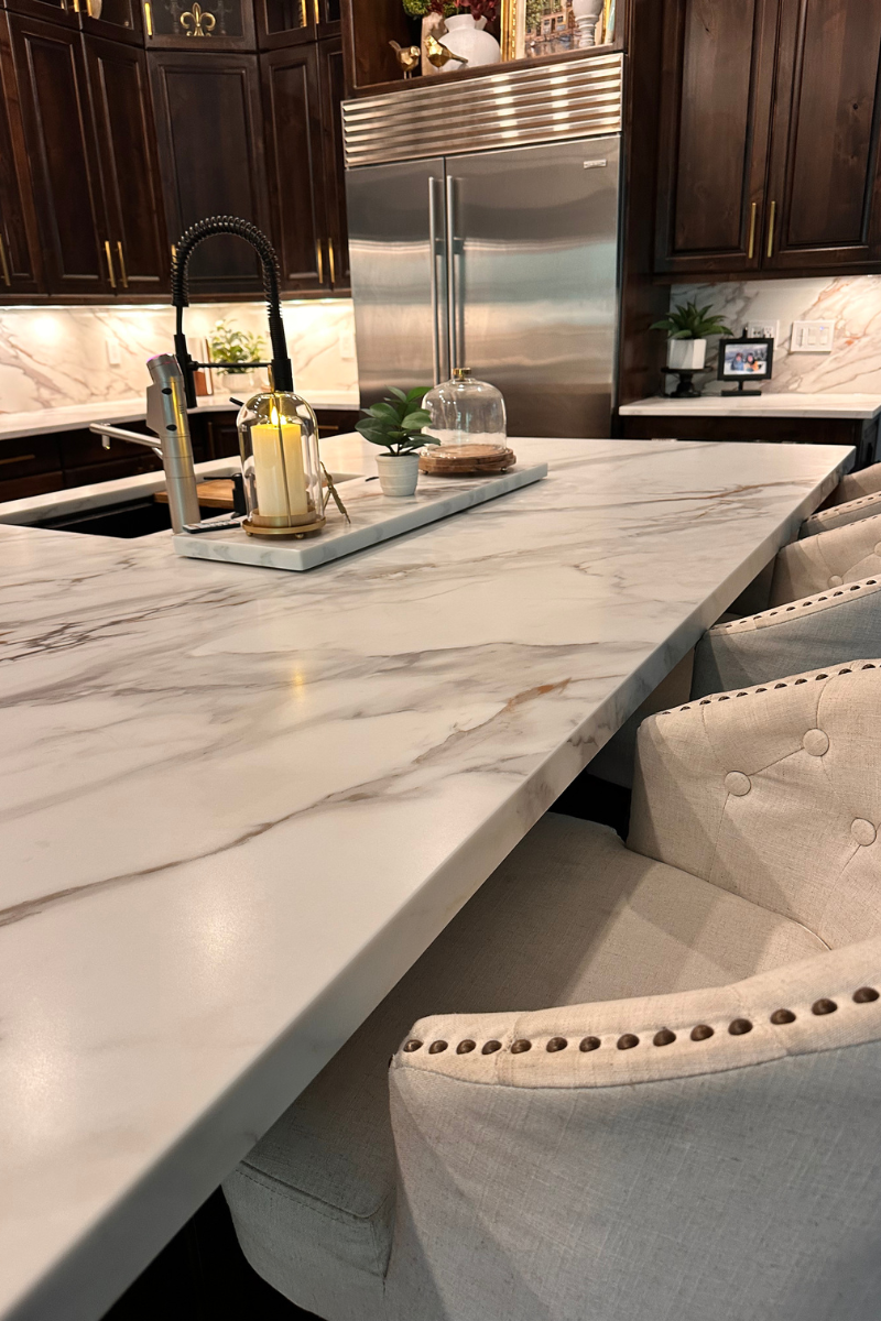 Marble dining table with beige upholstered chairs and condiments in a bright indoor setting