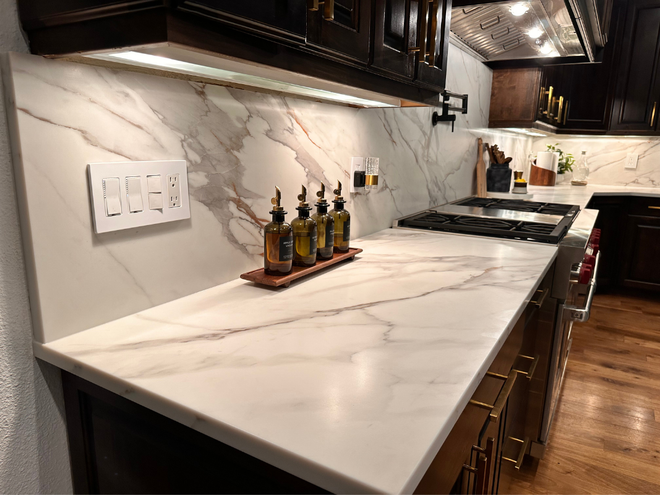 Modern kitchen countertop with marble backsplash, built-in stove, and condiments on a tray