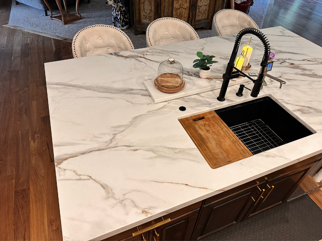 Modern kitchen island with white marble countertop, black faucet, and built-in sink and cooktop.