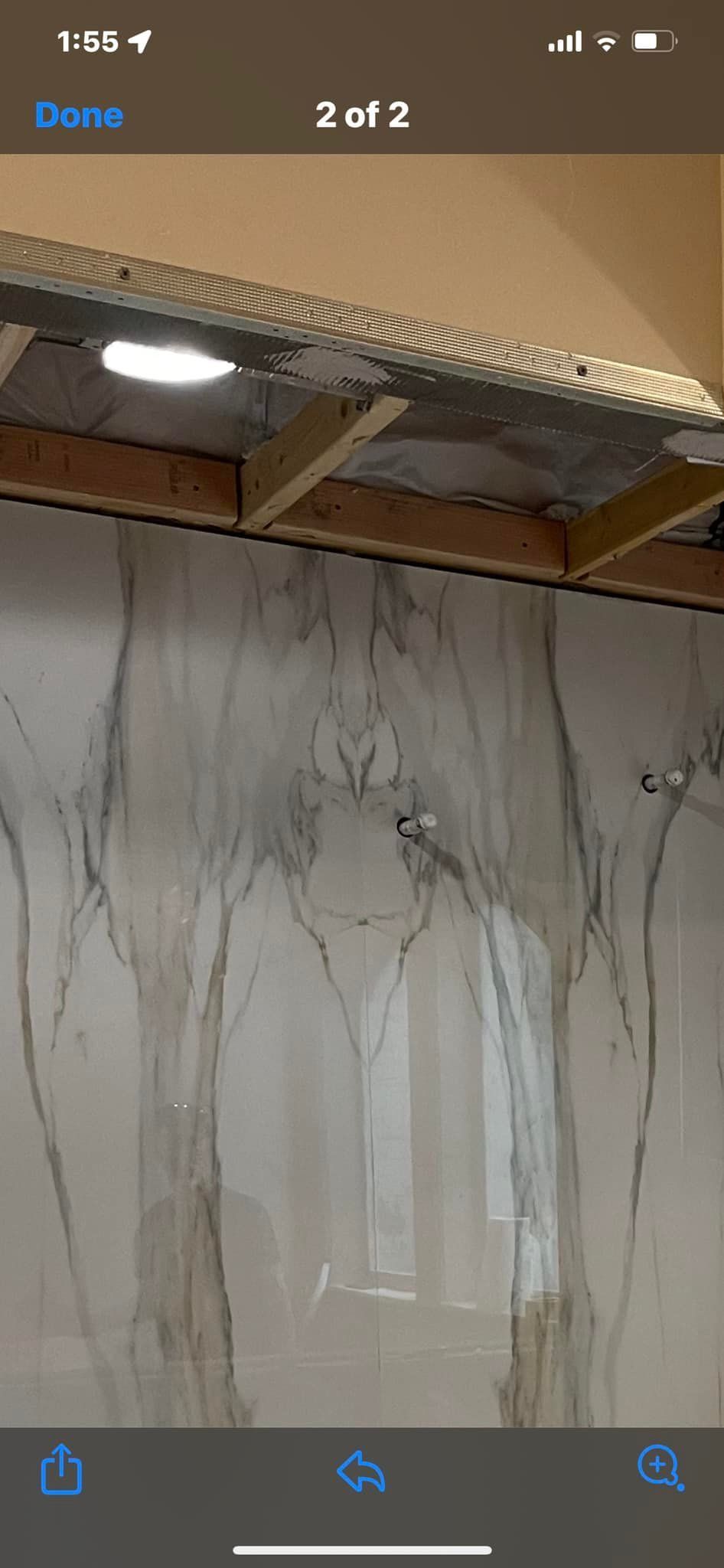 Marbled white wall panel under a wooden ceiling beam with a textured light fixture above.