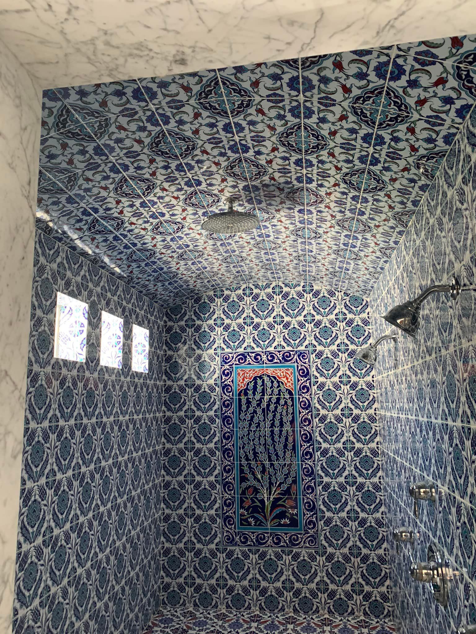 Blue-and-white tiled bathroom with a shower, small windows, and a mirror cabinet