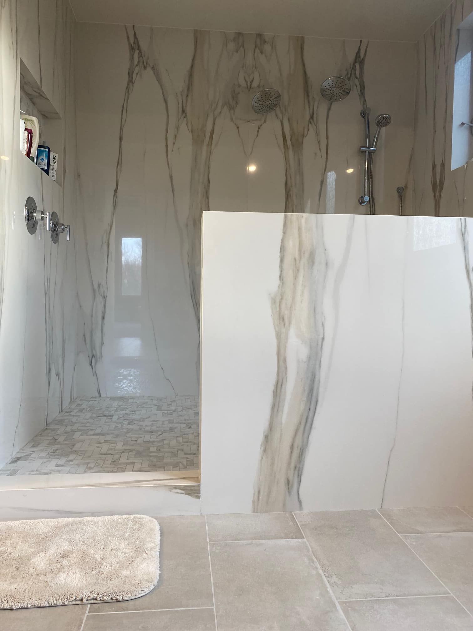 Modern marble-tiled bathroom with walk-in shower and partial white partition wall
