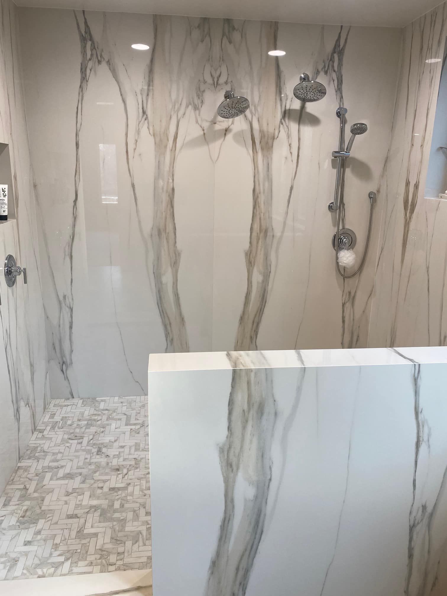 Modern marble-tiled shower with multiple showerheads and mosaic floor tiles