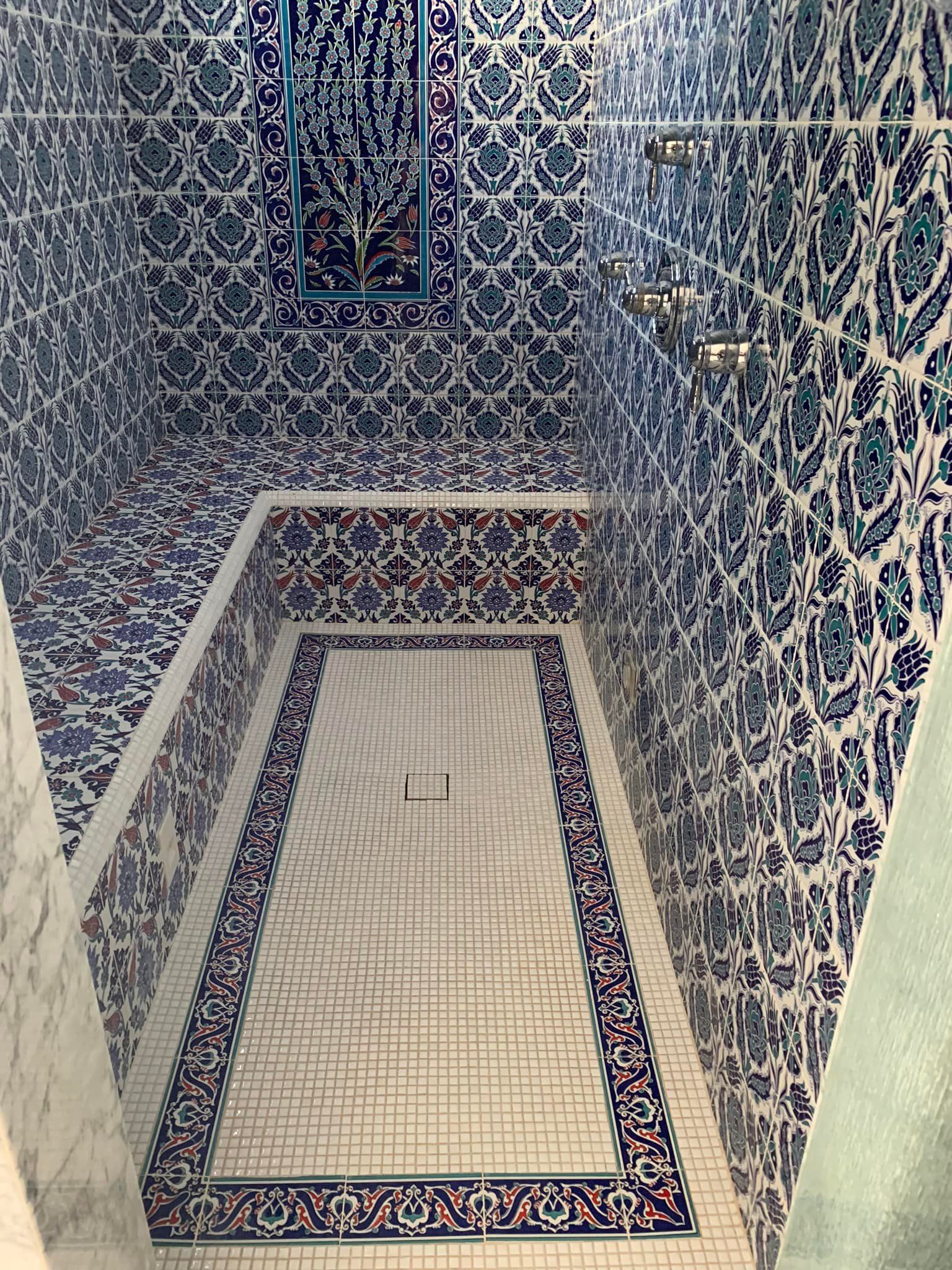 Narrow tiled pool or bath with blue-and-white mosaic walls and a rectangular opening at the bottom.