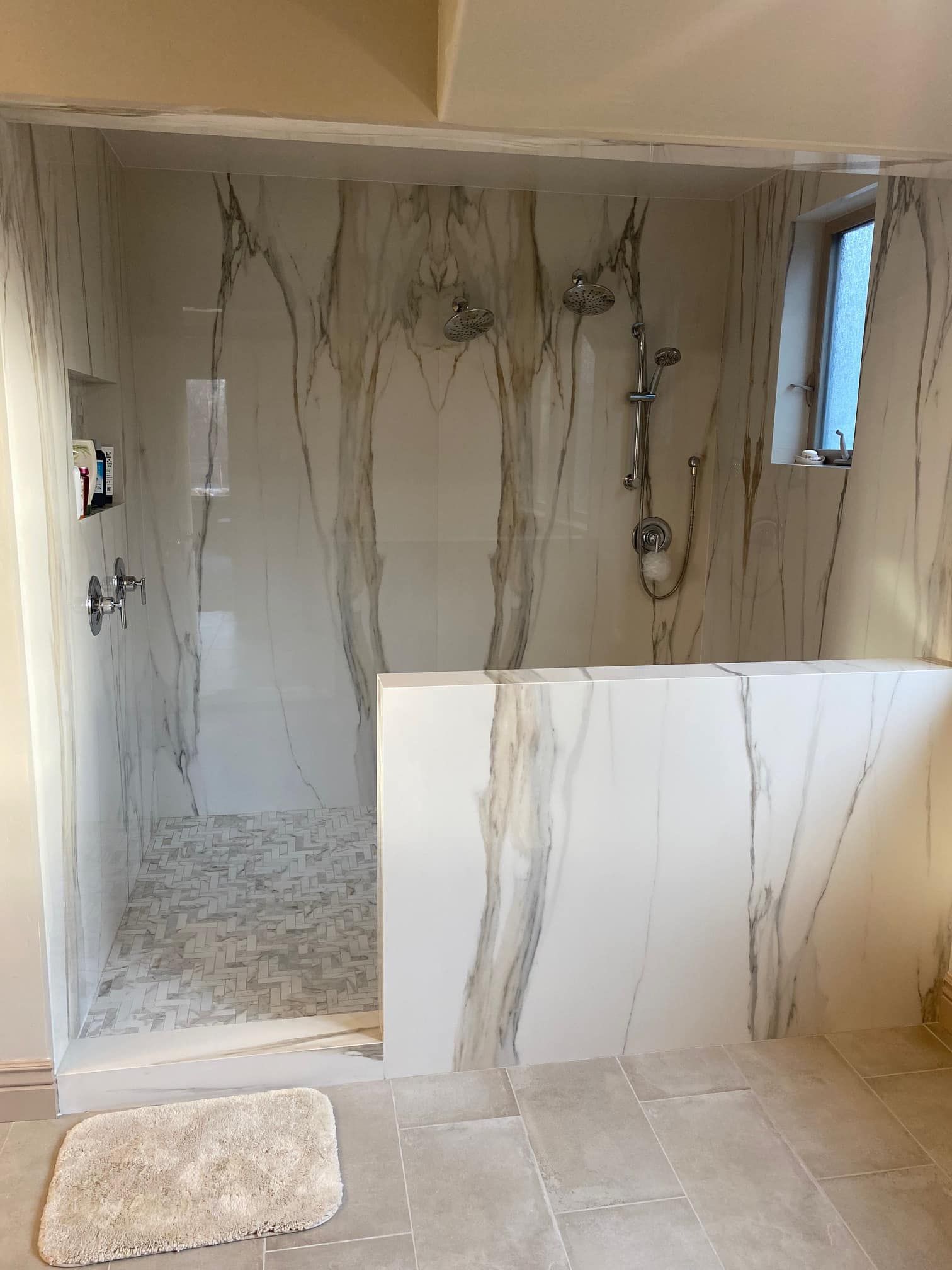 Small tiled bathroom shower area with unfinished walls and exposed plumbing.
