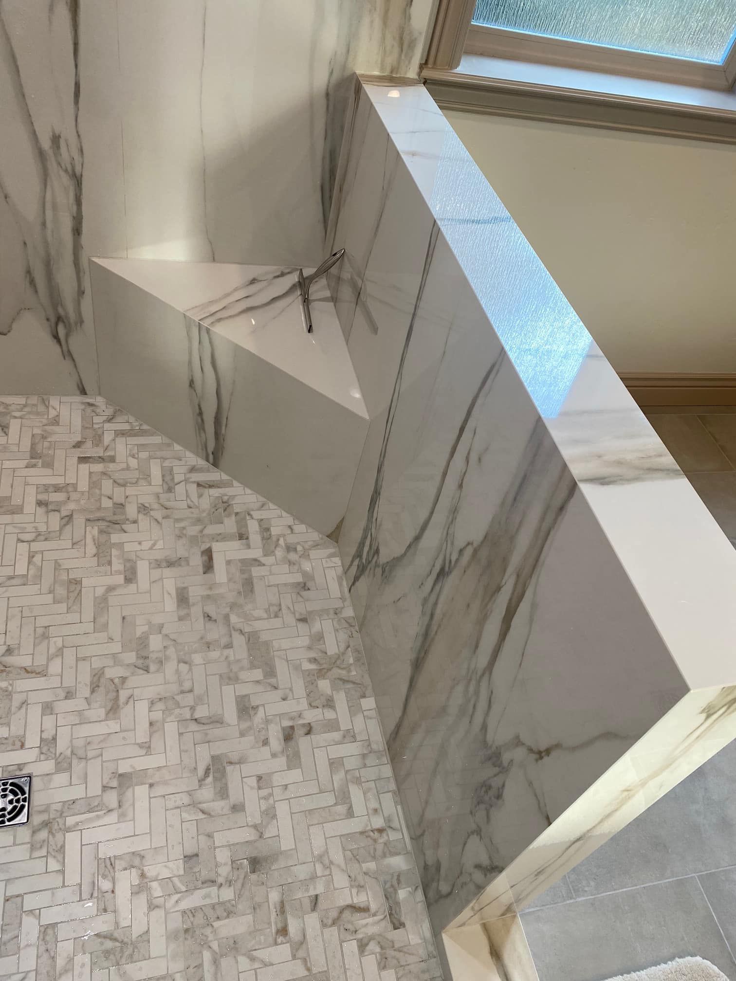 Marble staircase with white geometric railing and light patterned floor in a modern interior