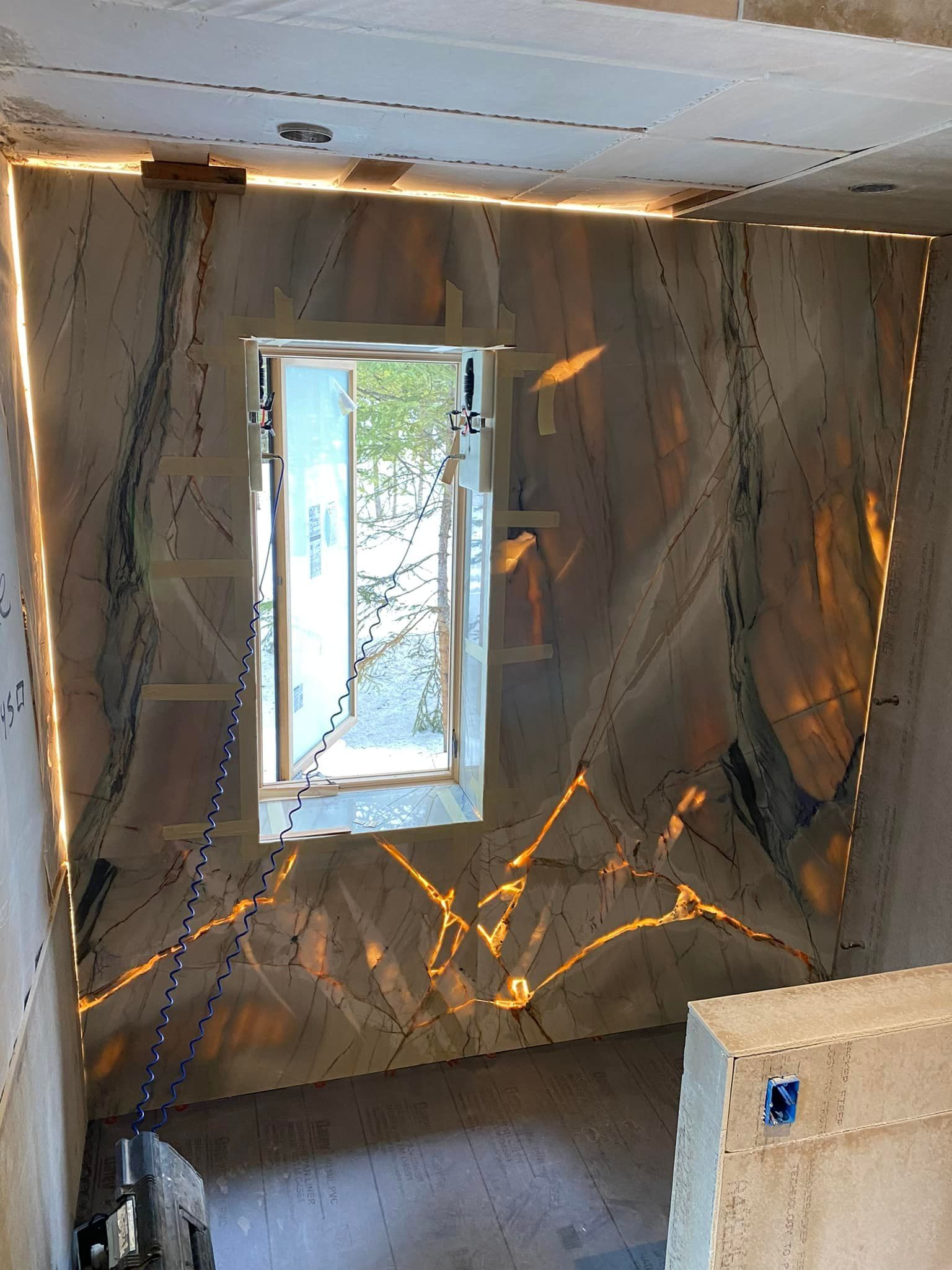Small room under construction with insulated walls, a window, and exposed flooring.