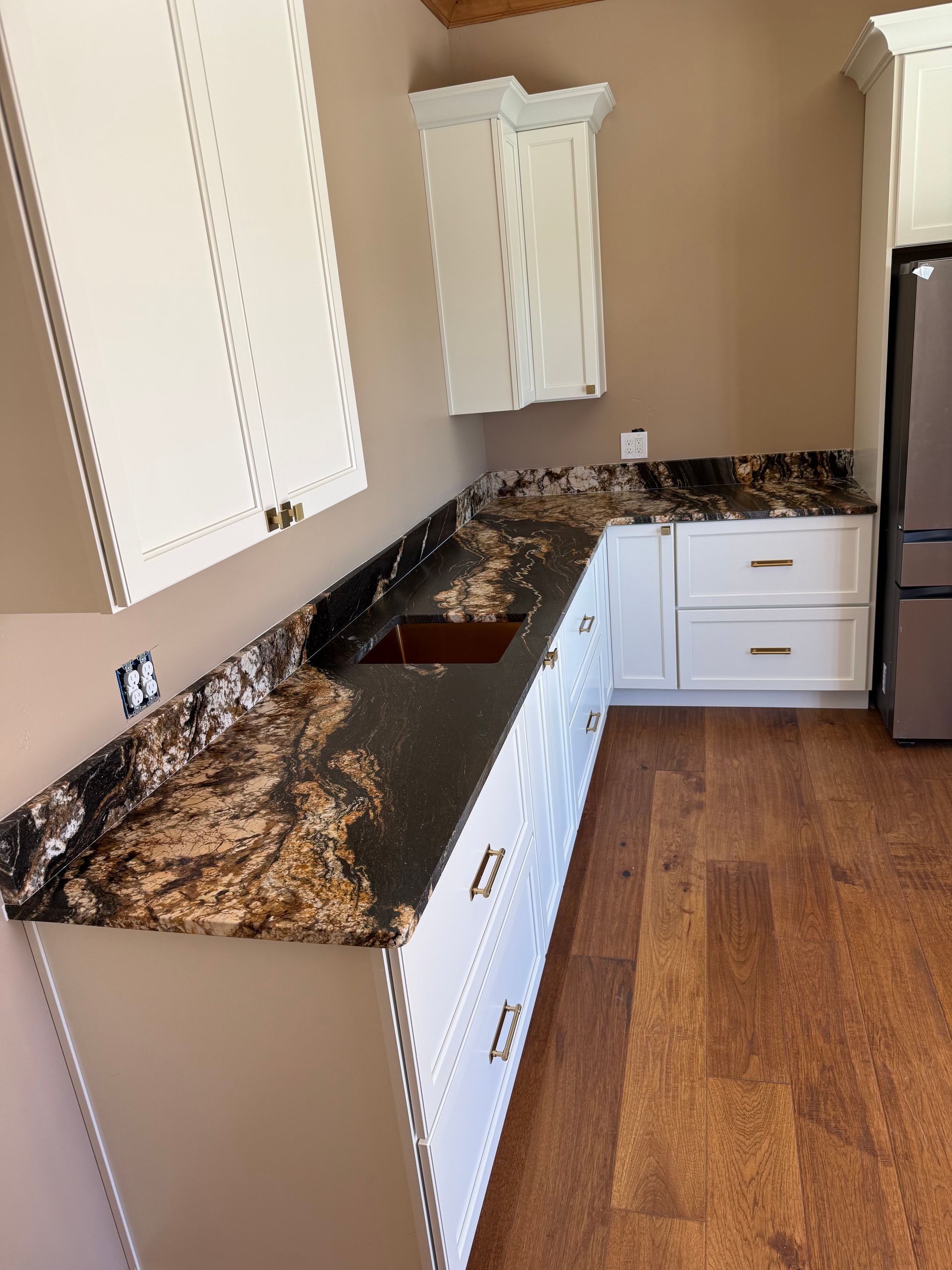 Small kitchen with white cabinets, granite countertops, and stainless steel refrigerator.