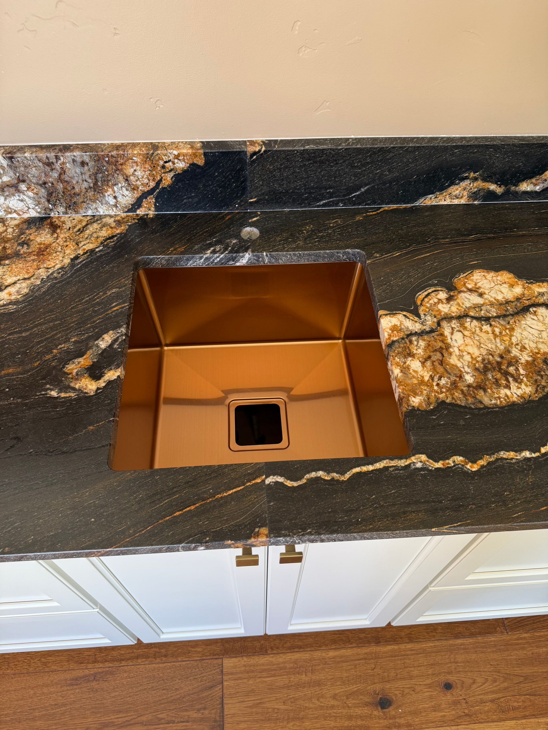 Copper rectangular ceiling vent with a black square opening on a patterned dark countertop.