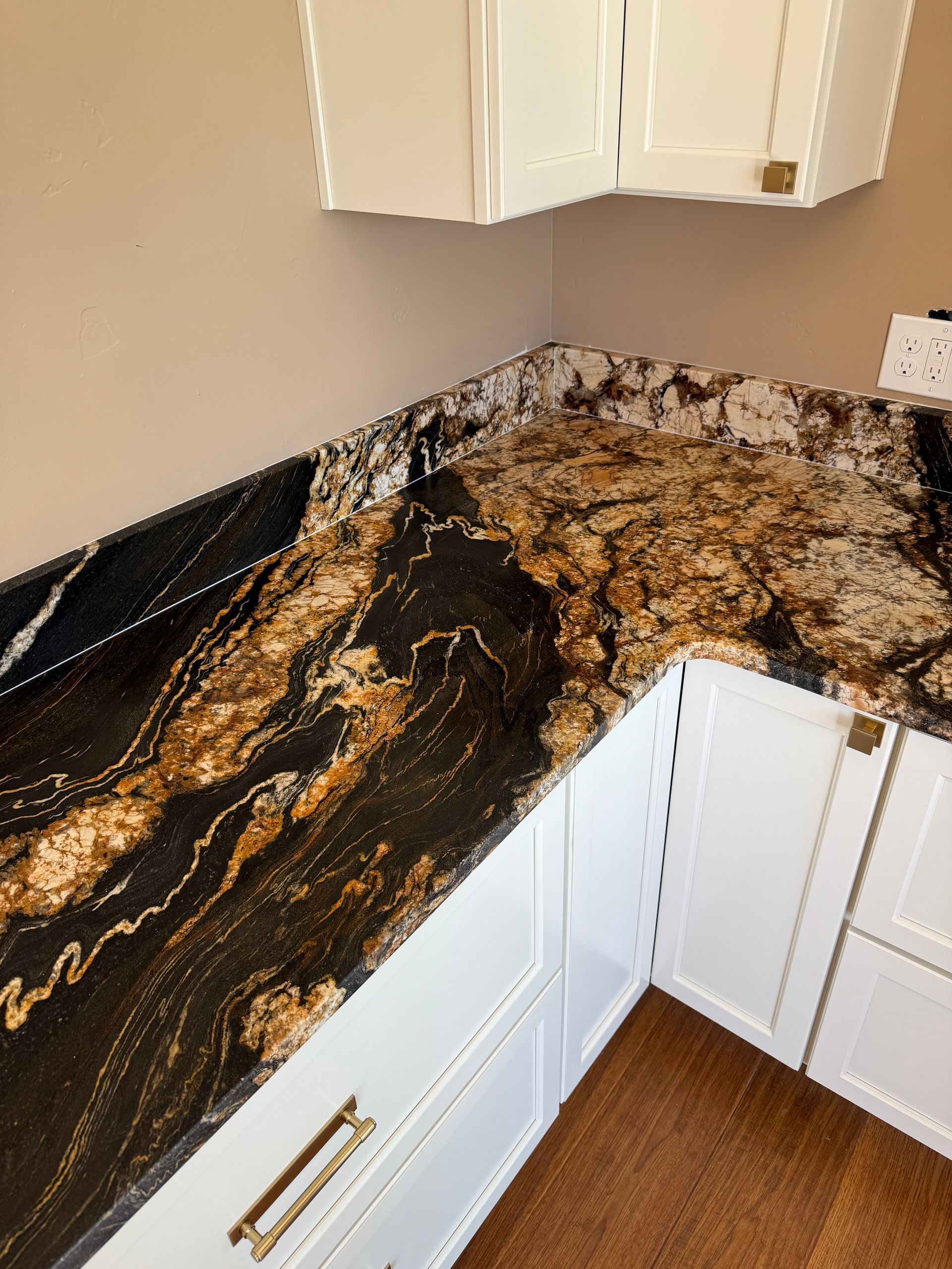 Granite kitchen countertop with black, gold, and white veining in an L-shaped corner cabinet area