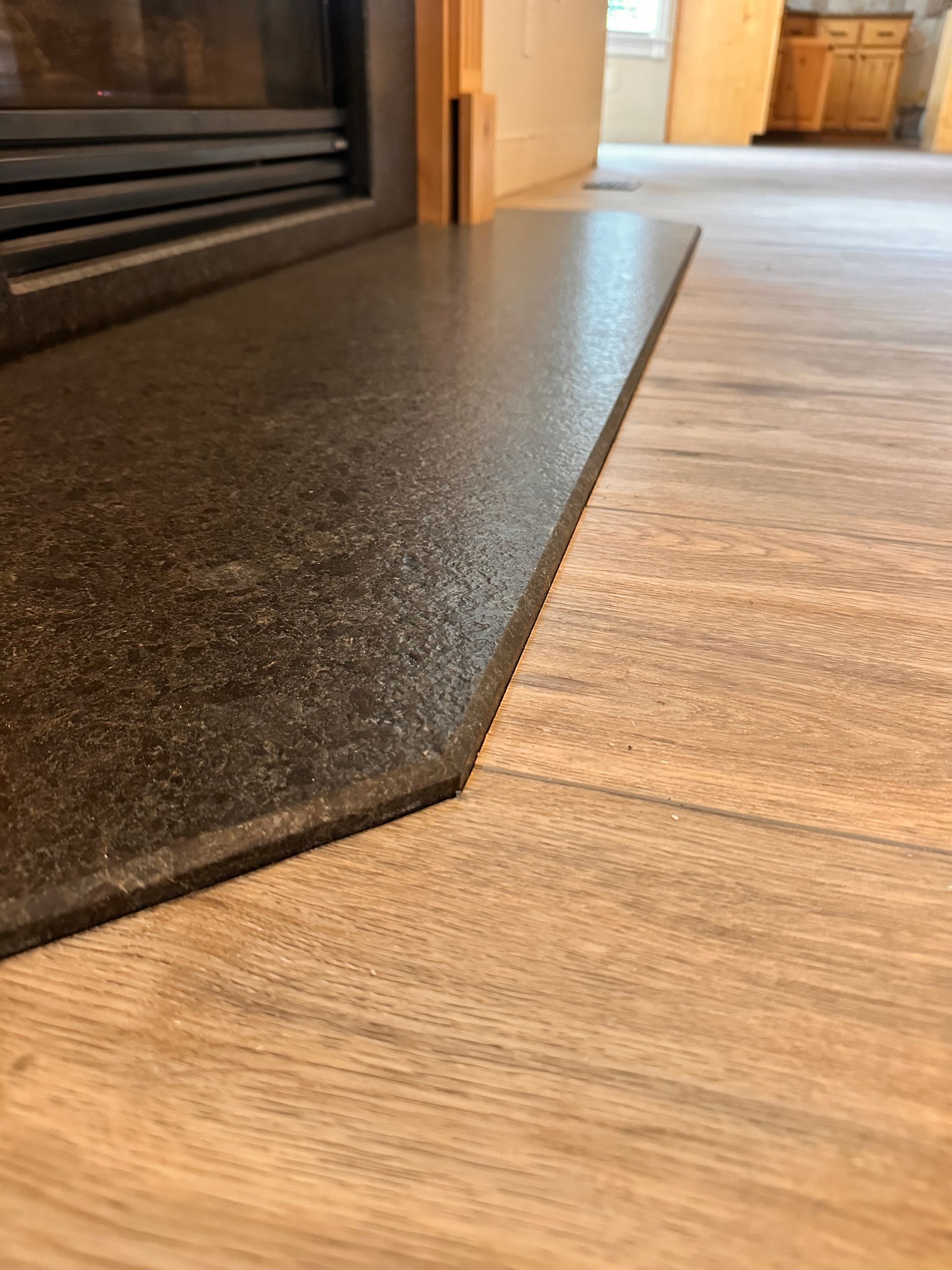 Black fireplace hearth edge on wood floor inside a room