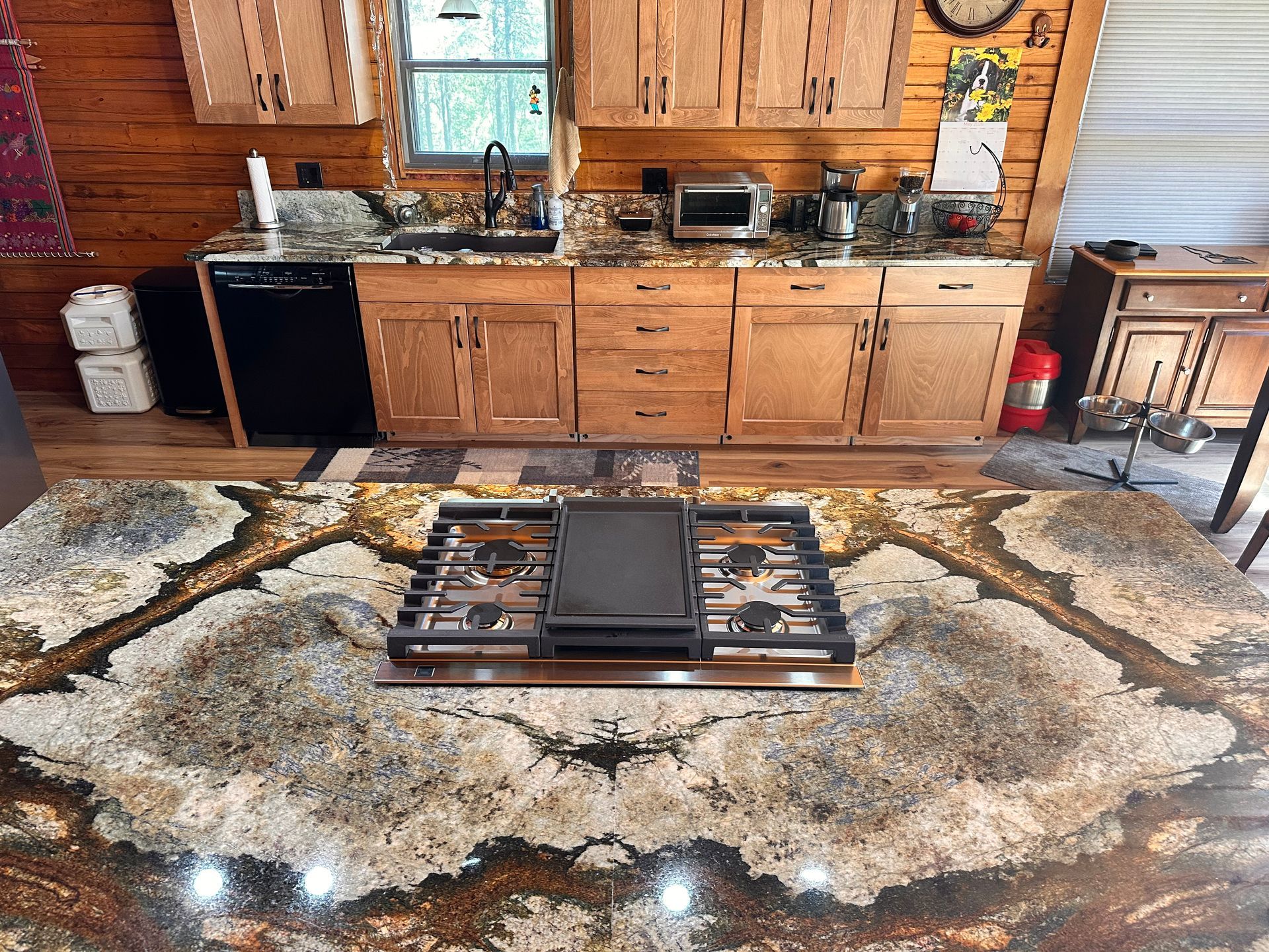 Rustic kitchen with wooden cabinets and a large patterned cowhide rug under a low coffee table.