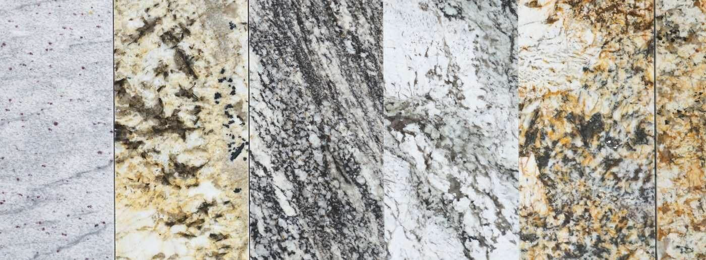 Four vertical stone slabs with different gray, white, beige, and yellow speckled textures