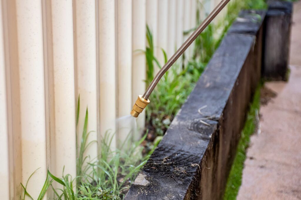 Sprayer Nozzle Applying Herbicide to Weeds Along a Fence and Stone Border — Dusted Pest Management in West Wyalong, NSW