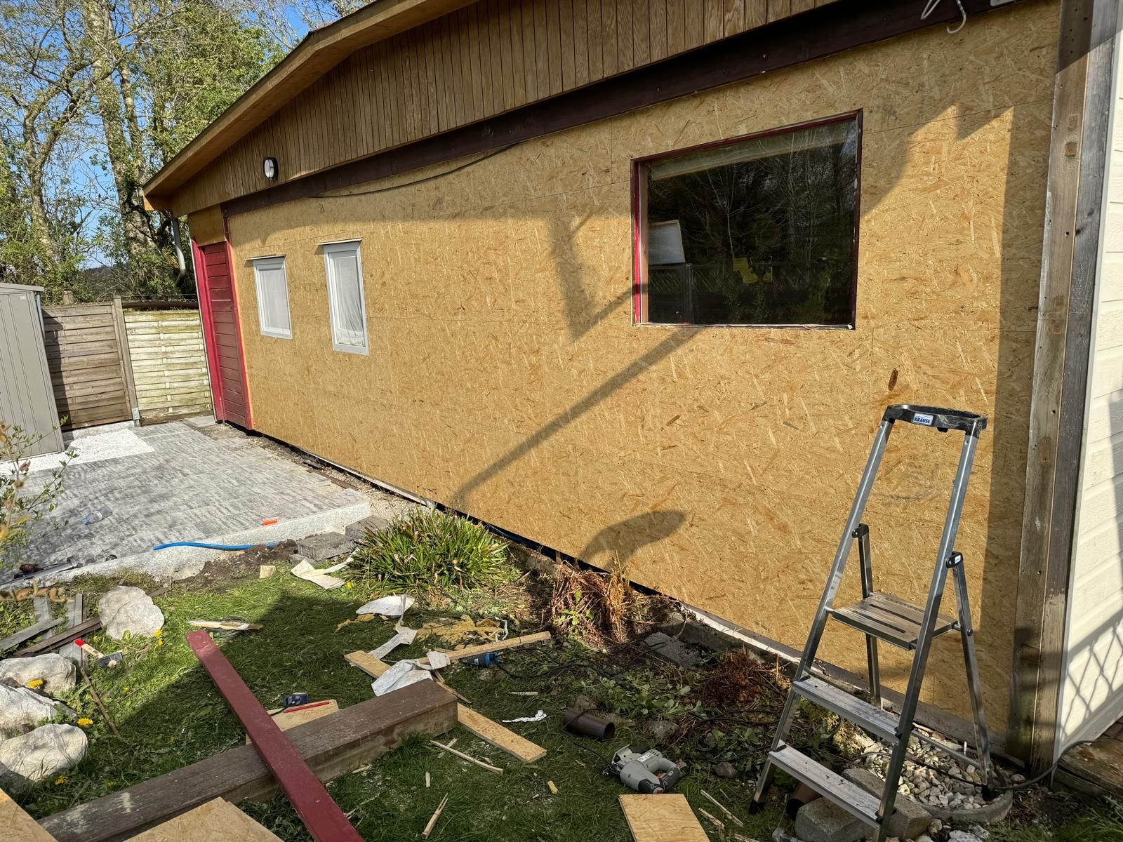 Échelle de chantier à côté d'une maison beige avec un nouveau revêtement mural et une fenêtre en construction