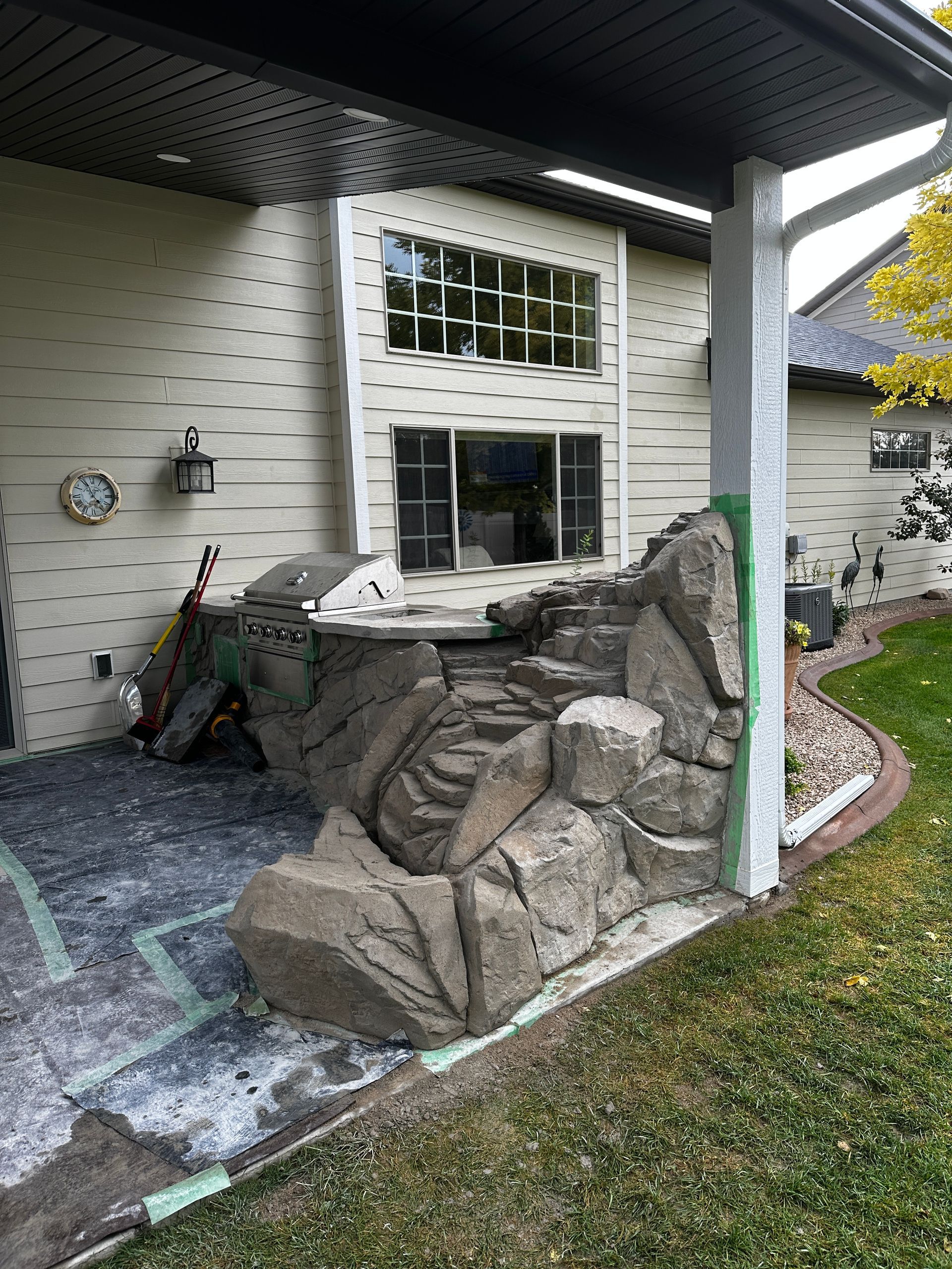 Backyard with a rock waterfall feature, patio, and house exterior.