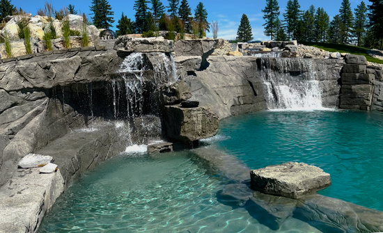 Waterfalls cascade into a turquoise pool surrounded by gray rock formations.