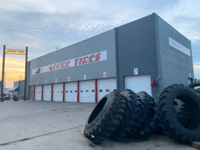 Moore Tires building with several garage bays and large tires in front.