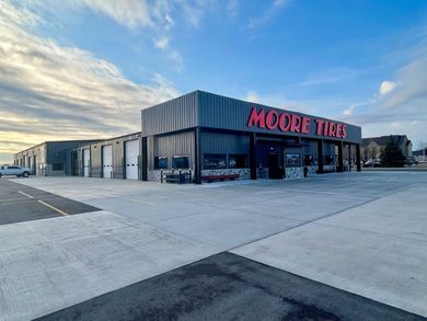 Moore Tire building with red logo under cloudy sky.