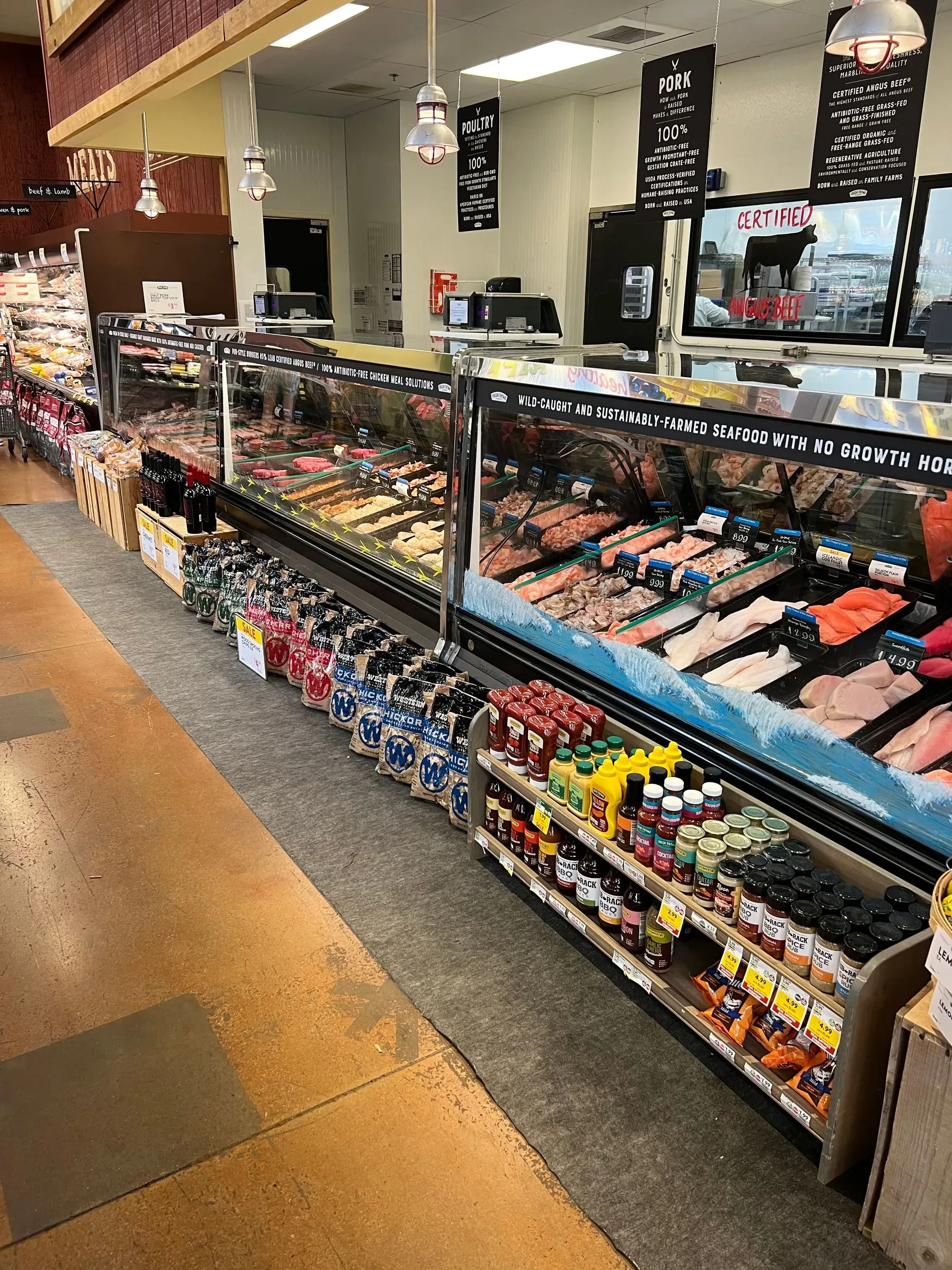 A grocery store seafood display with rows of chilled fish and prepared items.
