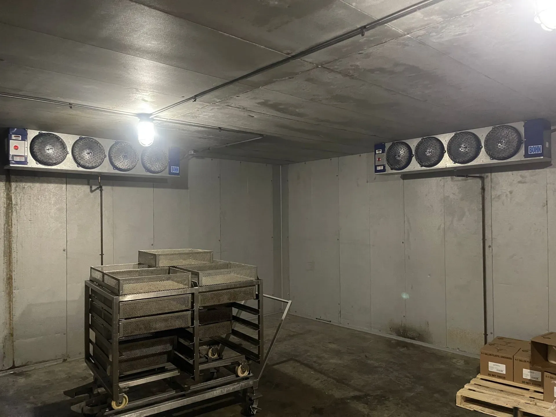 Cooler interior with two evaporator units, cart, and pallets.