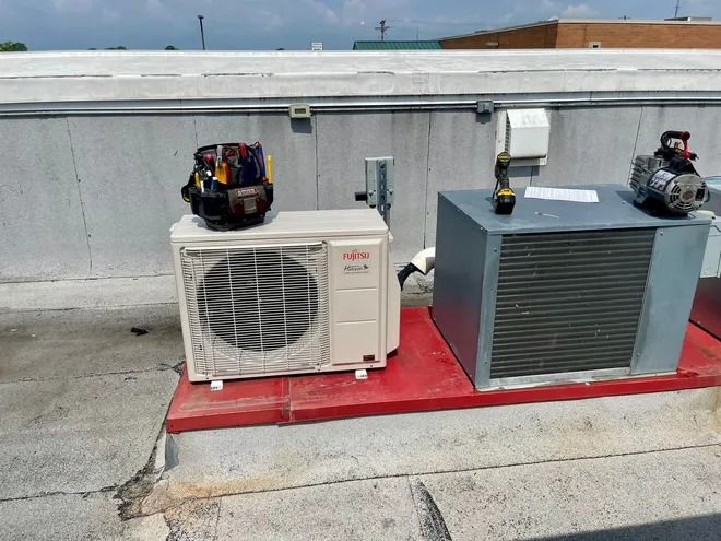 HVAC units on a flat rooftop with a tool bag, sunny day.