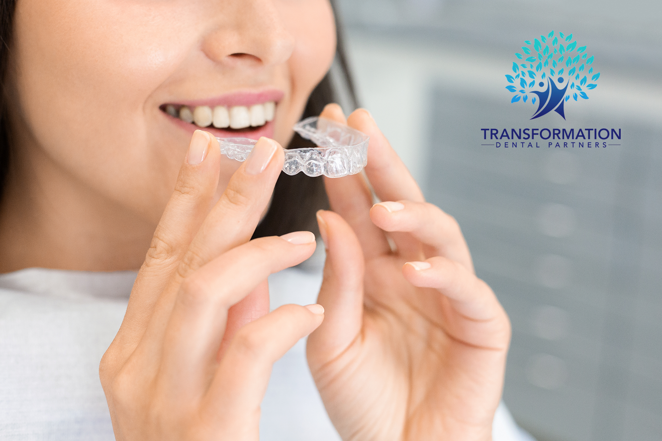 Woman holding a dental model showing a tooth implant, smiling. Blue background, white lab coat.