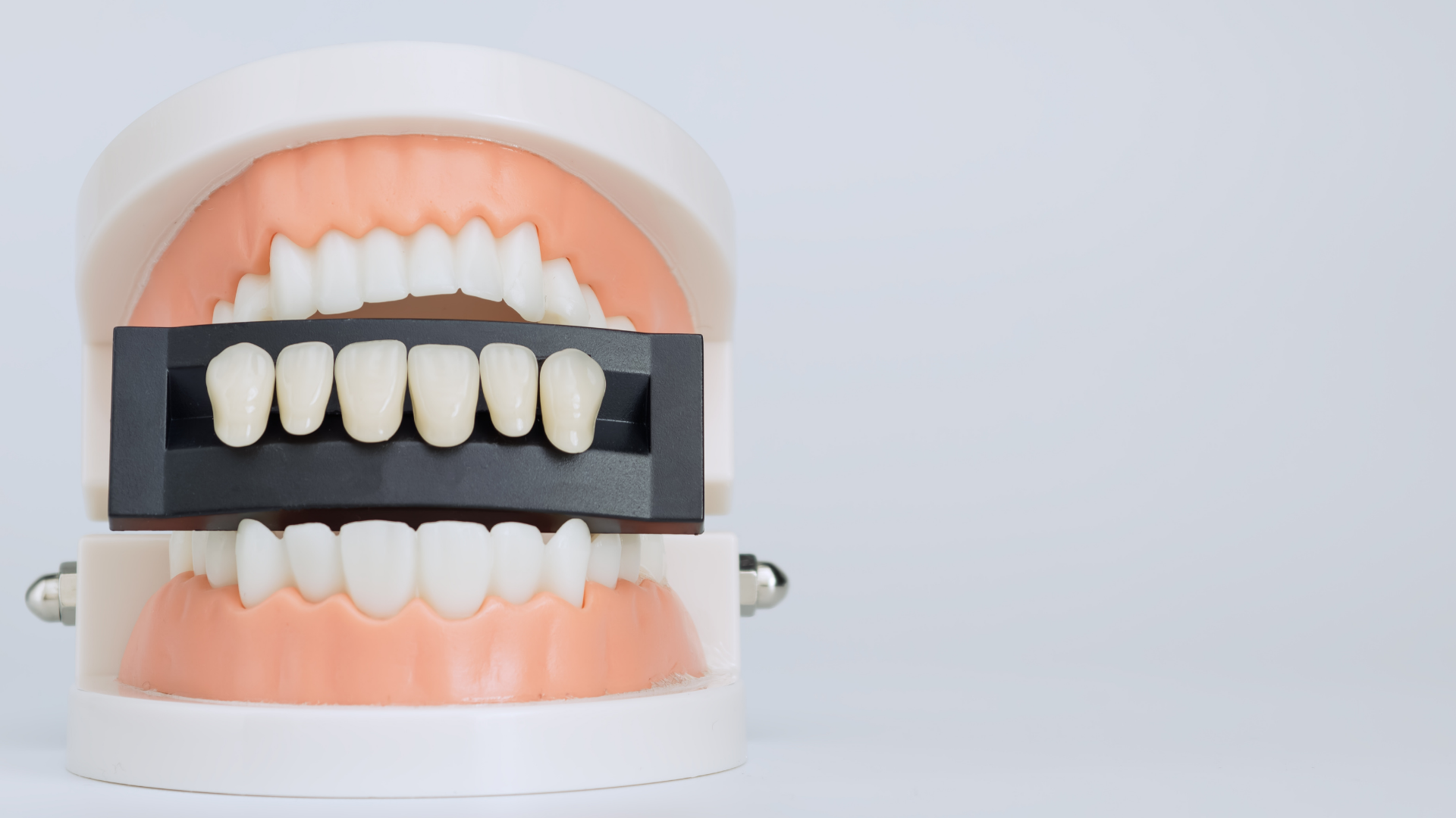 Dental mirror reflecting a white tooth model with an implant on a blue background