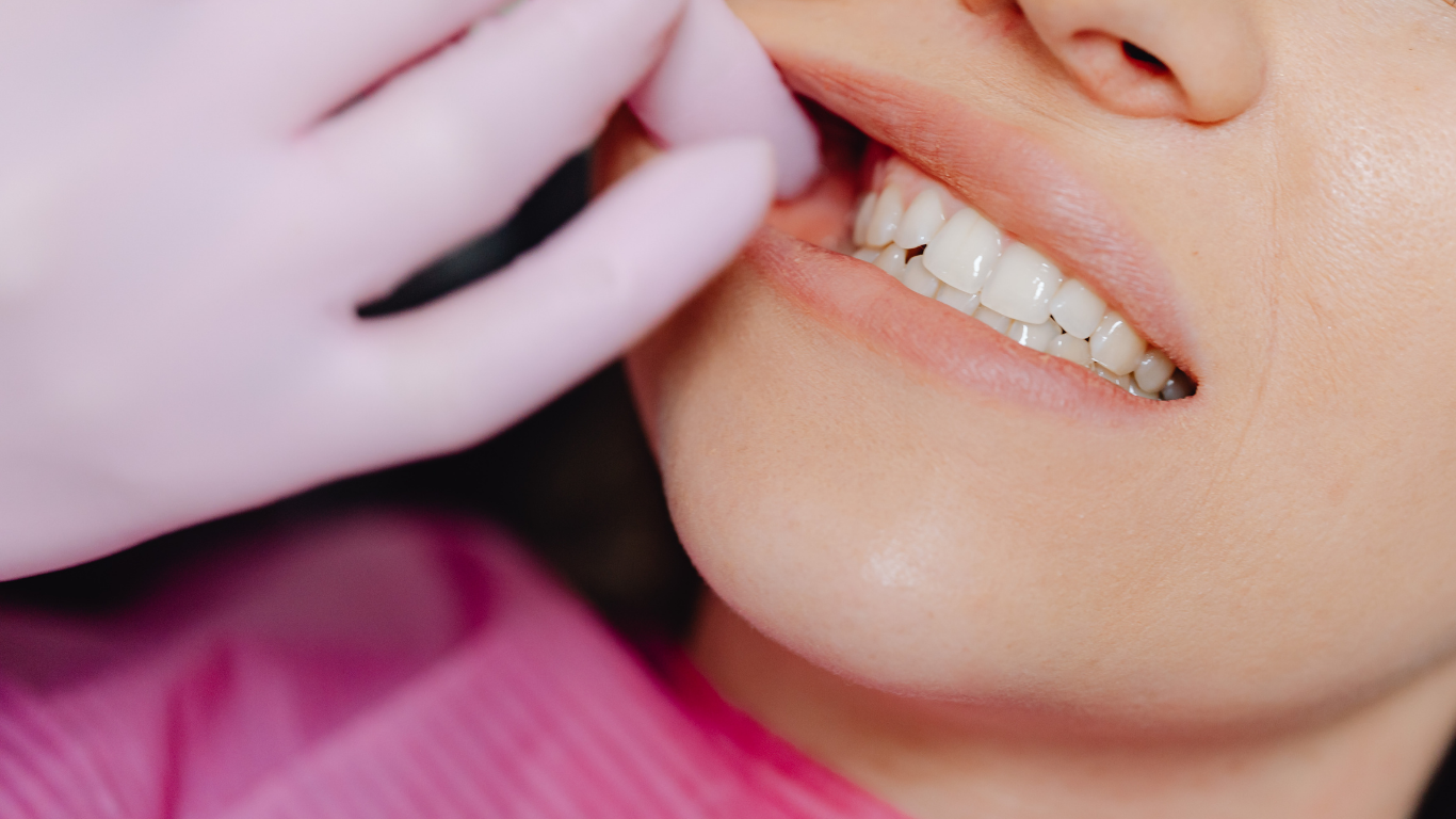 Dentist in white coat holding a dental mold and toothbrush, smiling against a blue background