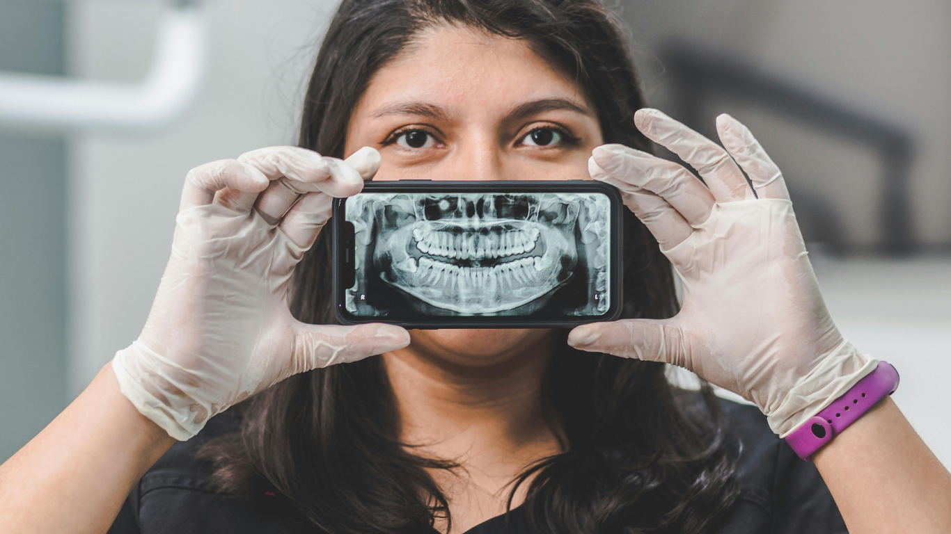 Person holding a smartphone showing an X-ray while wearing gloves in a clinical setting