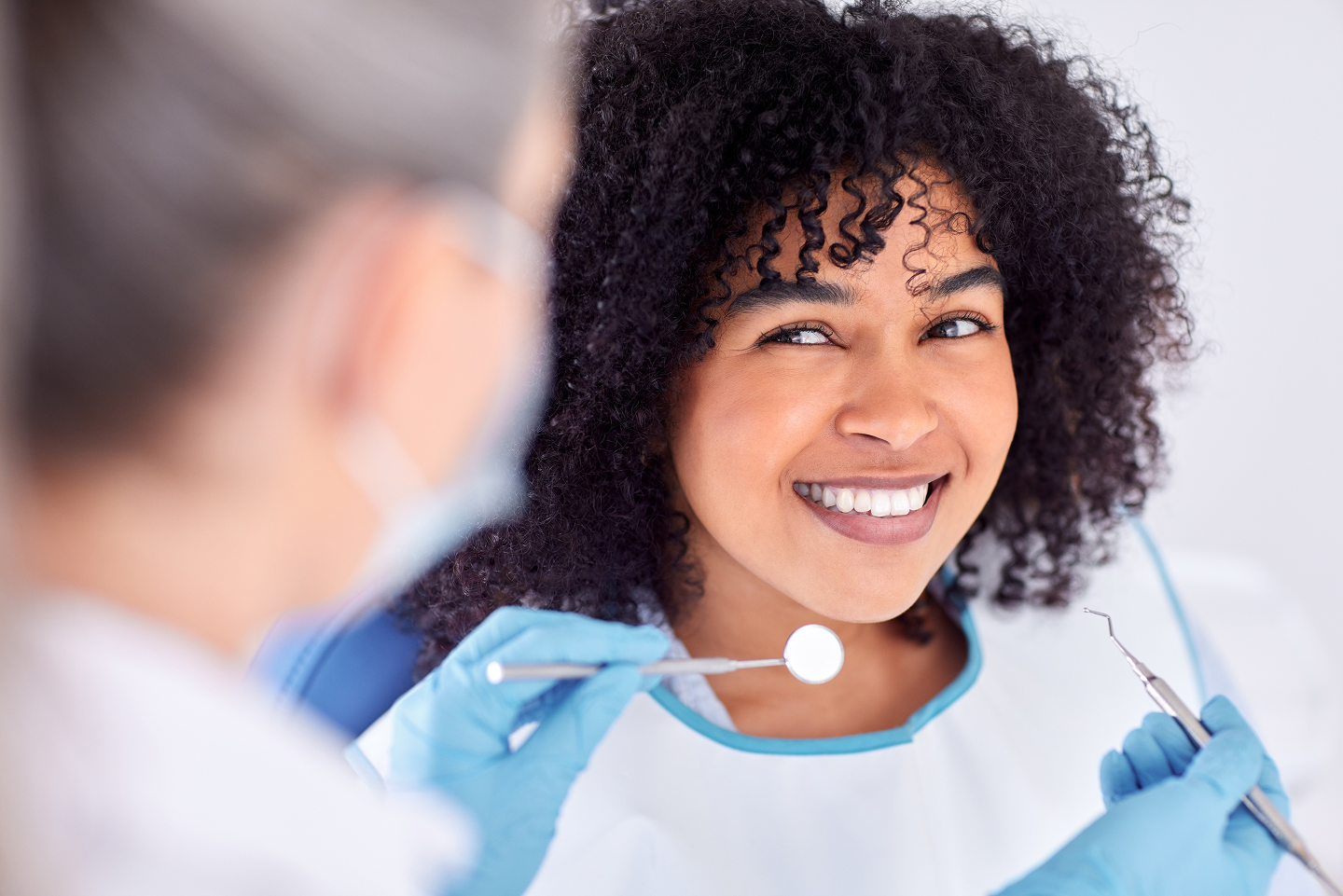 A woman is smiling while having her teeth examined by a dentist.