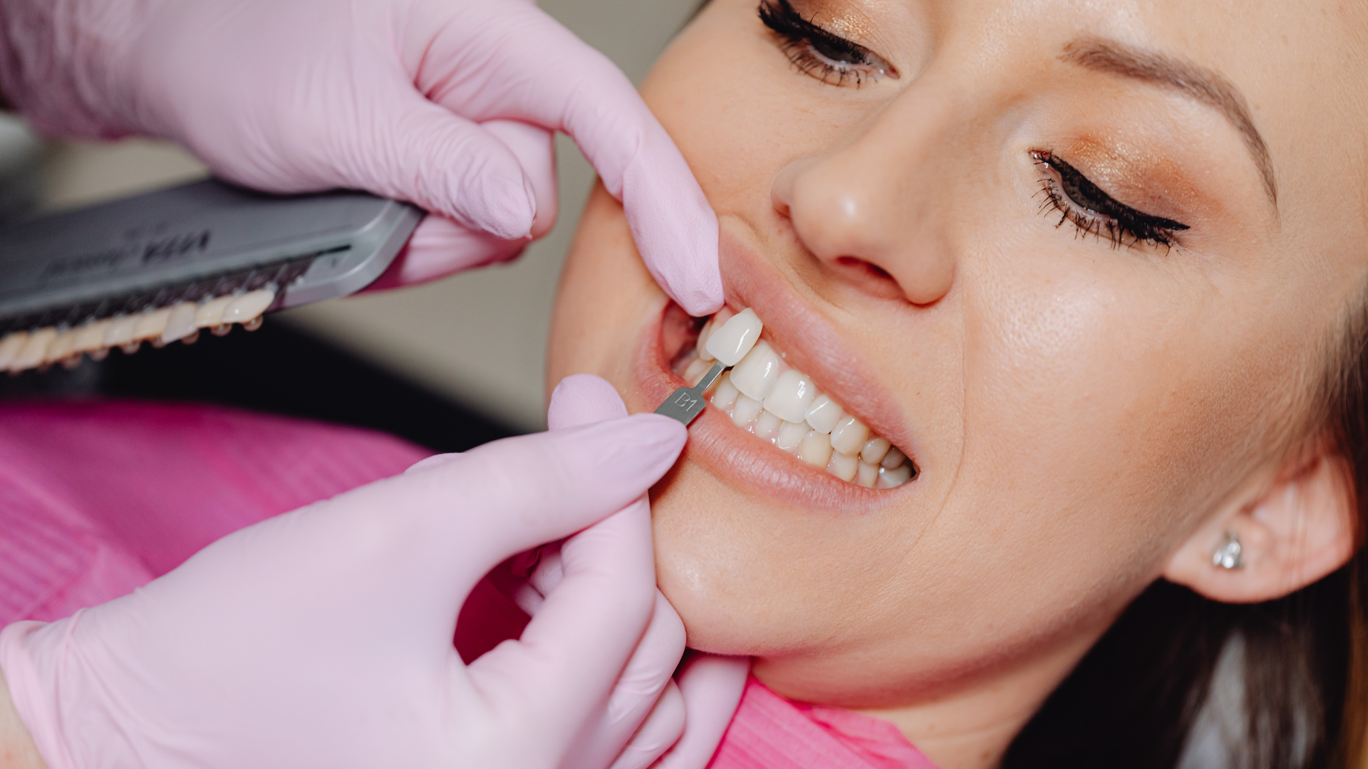 Dentist examining patient in dental chair, holding tools. Smiling patient, medical setting, logo visible.