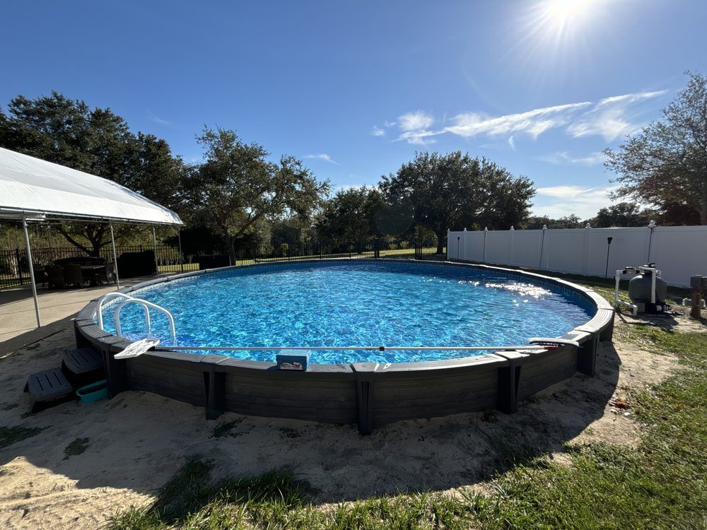 A large swimming pool in a backyard with a white tent in the background.